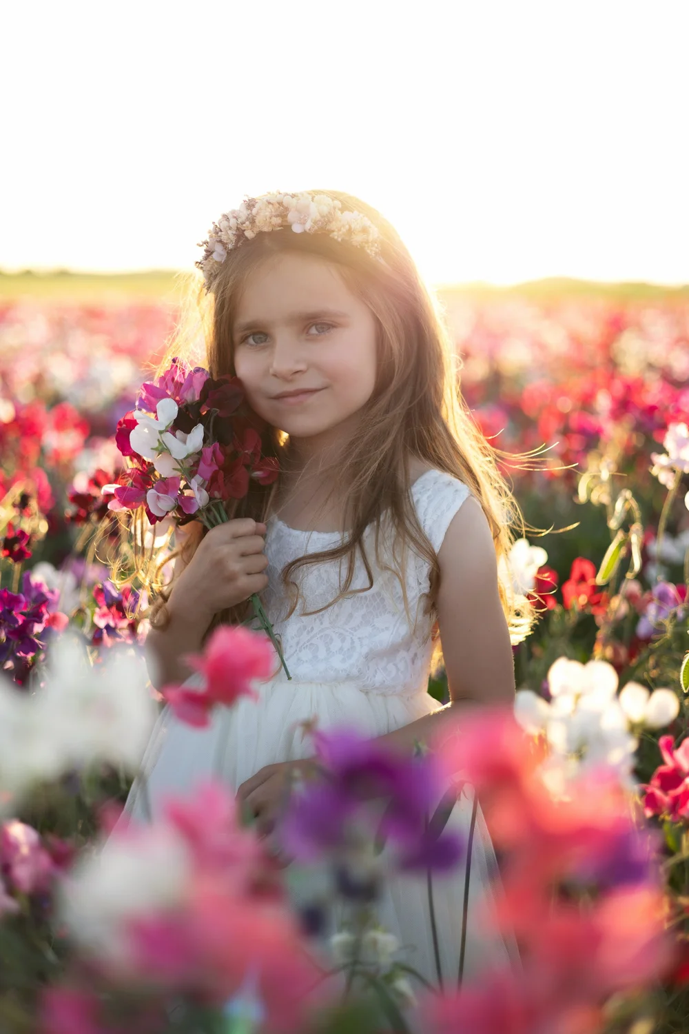 petite fille cheveux longs robe blanche dans les fleurs au coucher de soleil