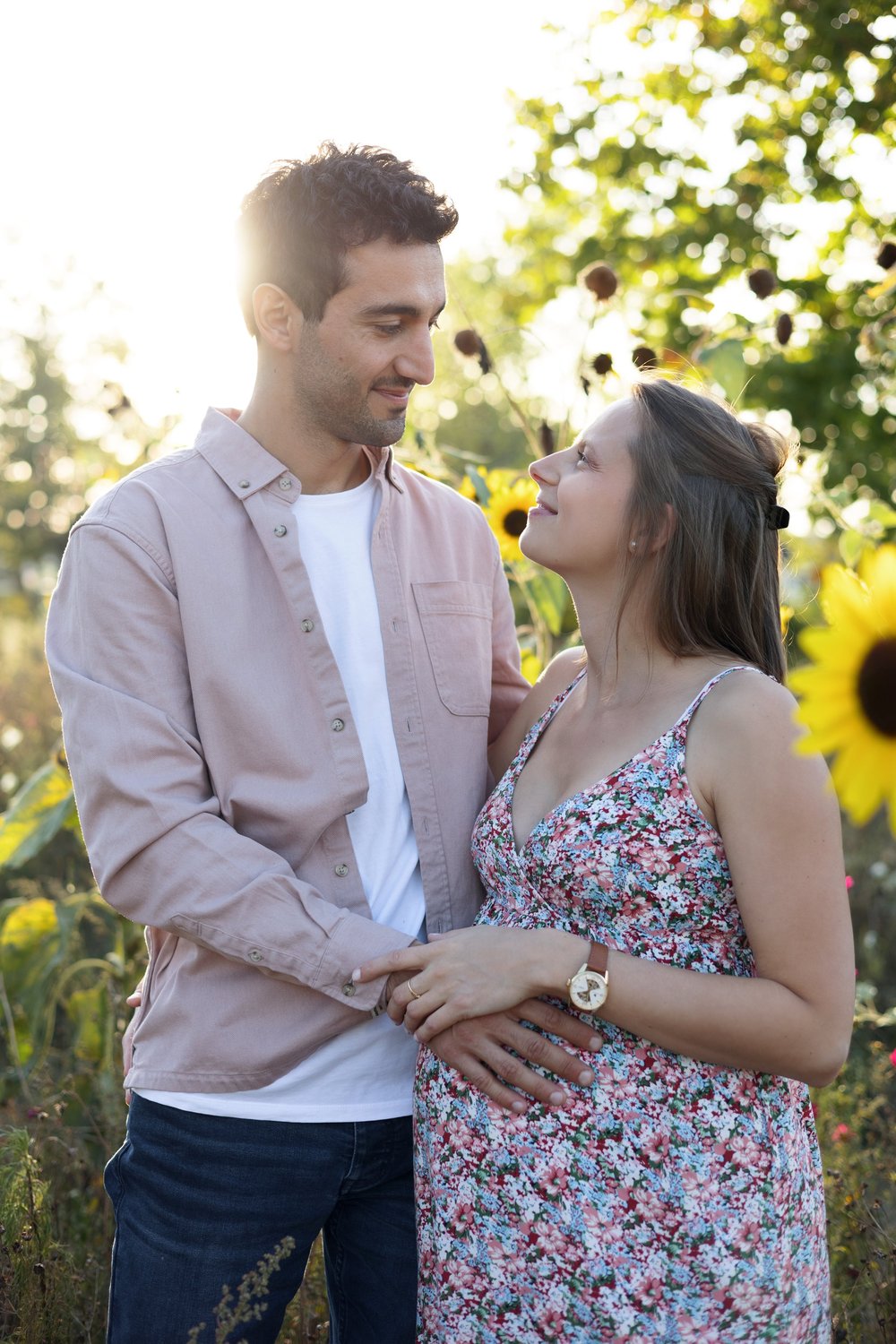 Couple dans un champ de tournesols, la femme enceinte en robe fleurie.