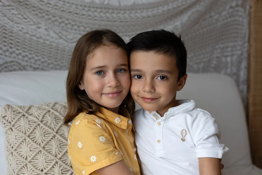 Frère et sœur assis sur un lit, en studio.