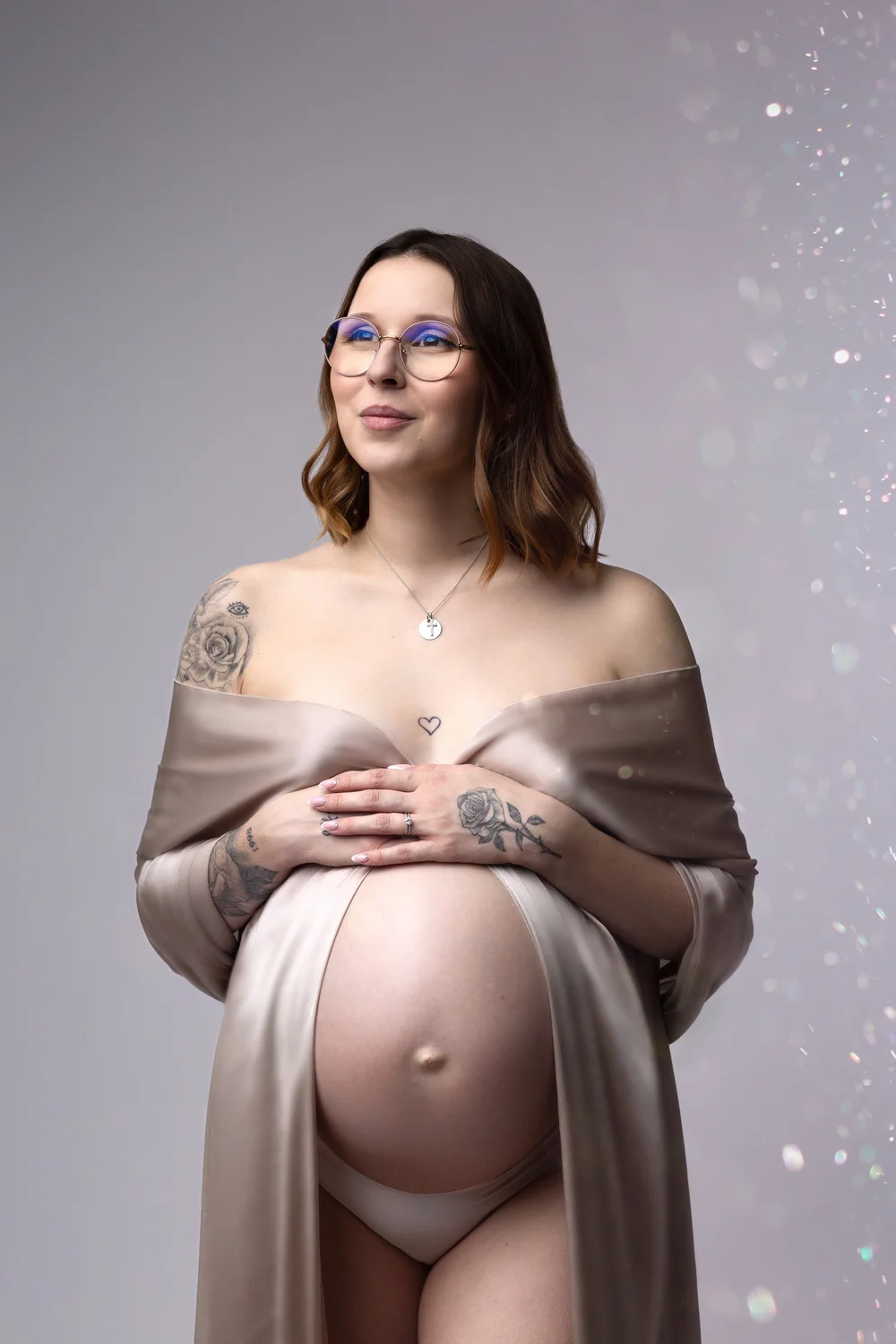 Femme enceinte drapée de satin clair sur fond pailleté.