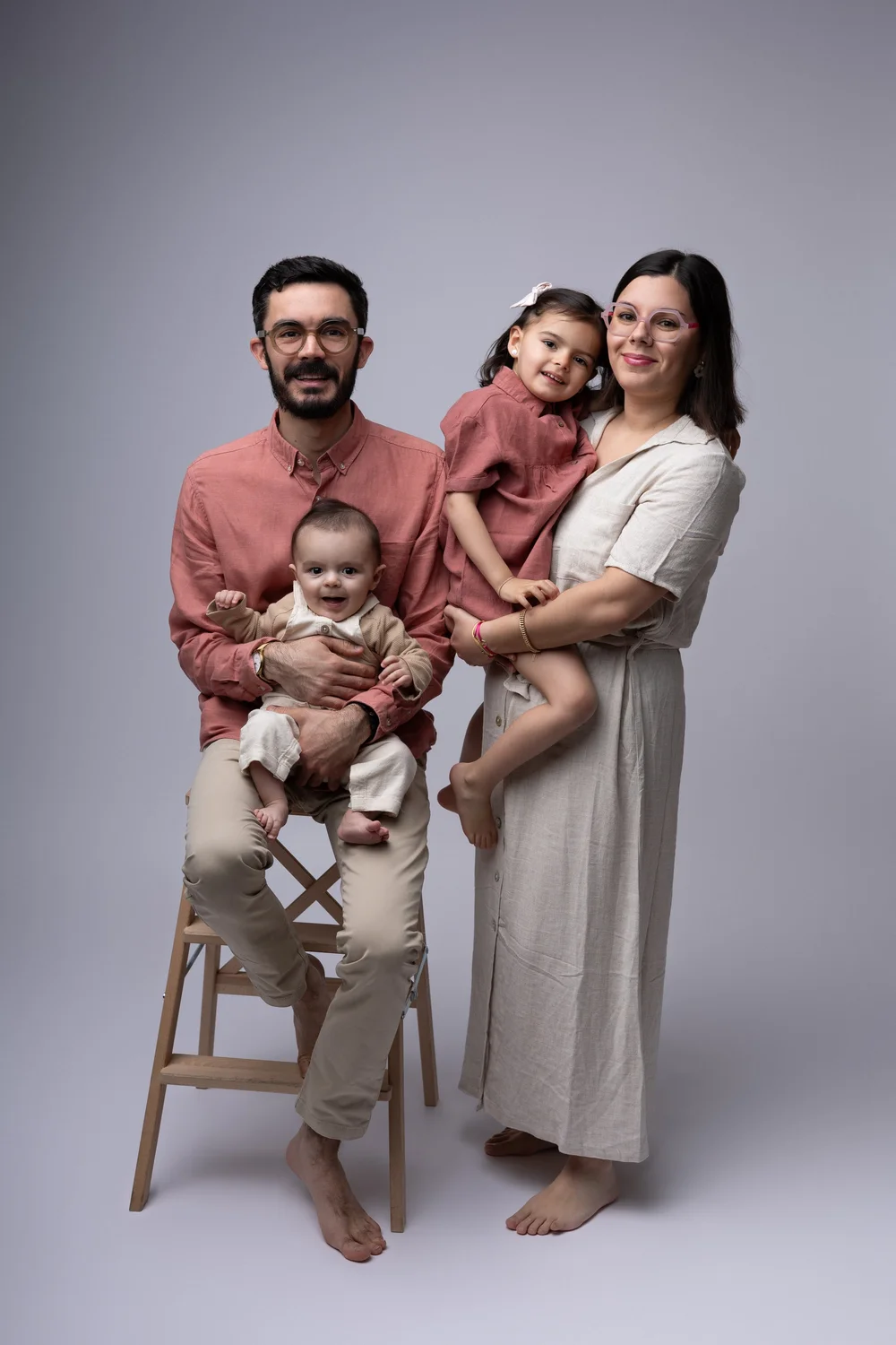 Famille de quatre en studio, le bébé assis sur une chaise haute.