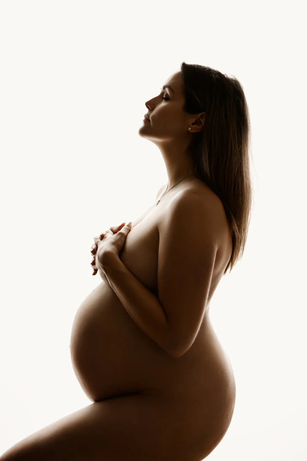 Silhouette de profil d’une femme enceinte, en contre-jour.