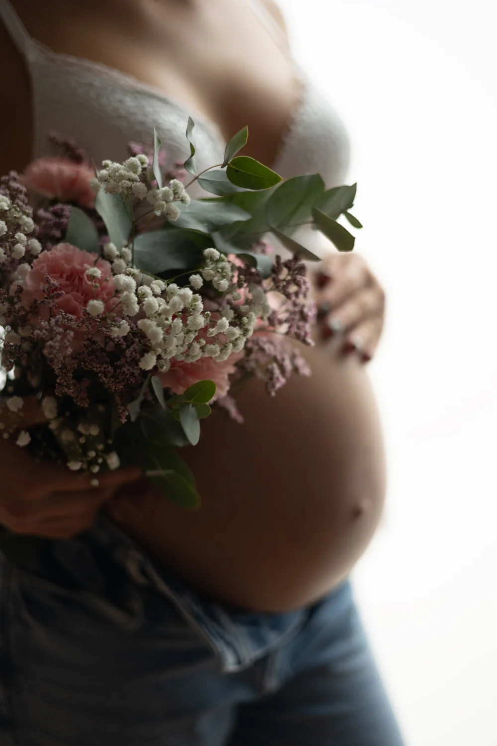Gros plan sur un ventre rond et un bouquet de fleurs.