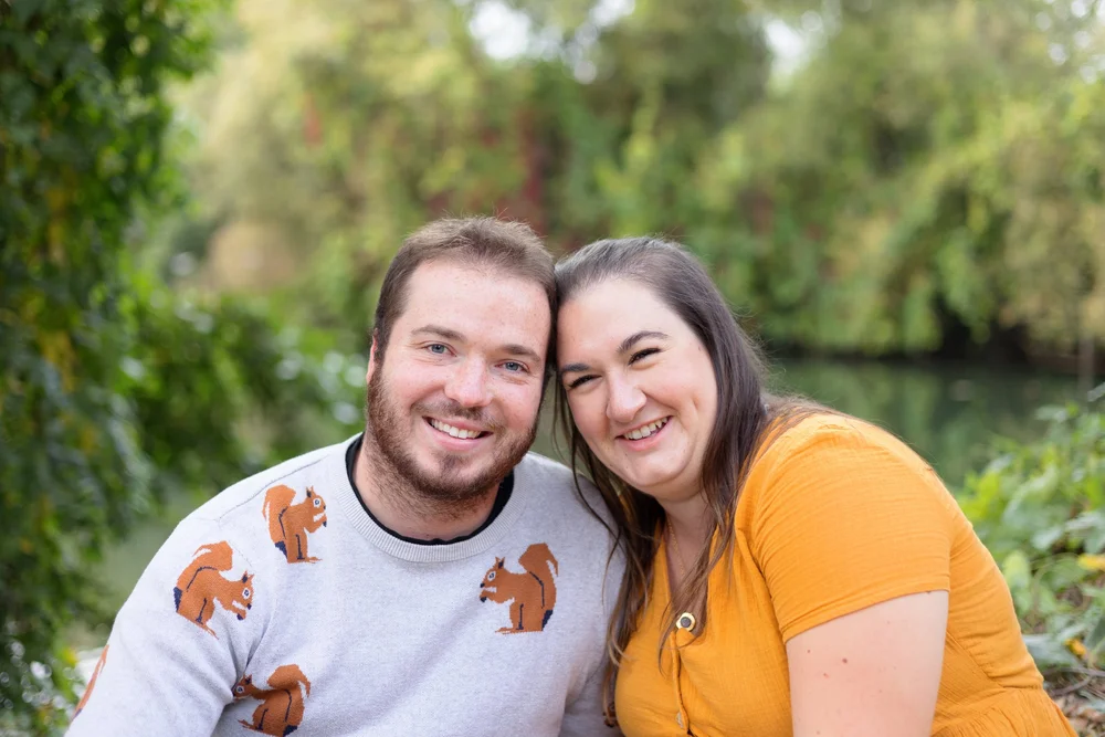 Couple souriant en pulls à motifs, en extérieur.