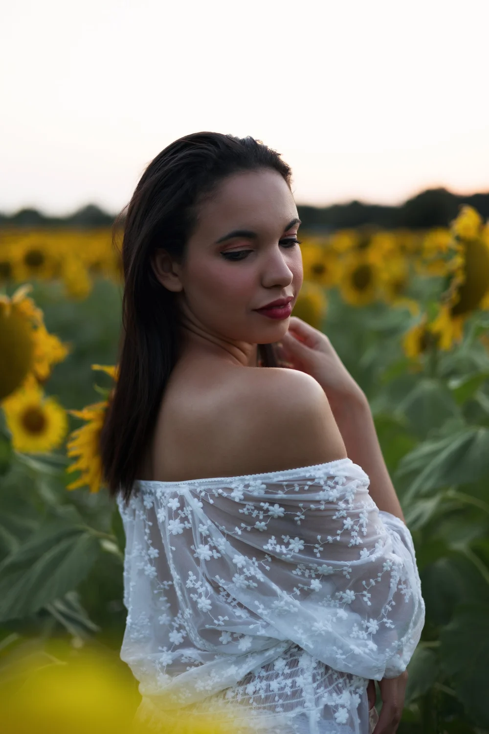 Femme en robe de dentelle blanche dans un champ de tournesols.