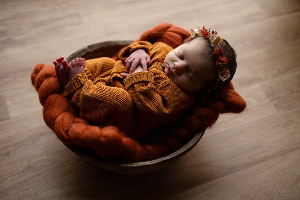 Nouveau-né endormi emmailloté de rouille dans une corbeille garnie de laine.