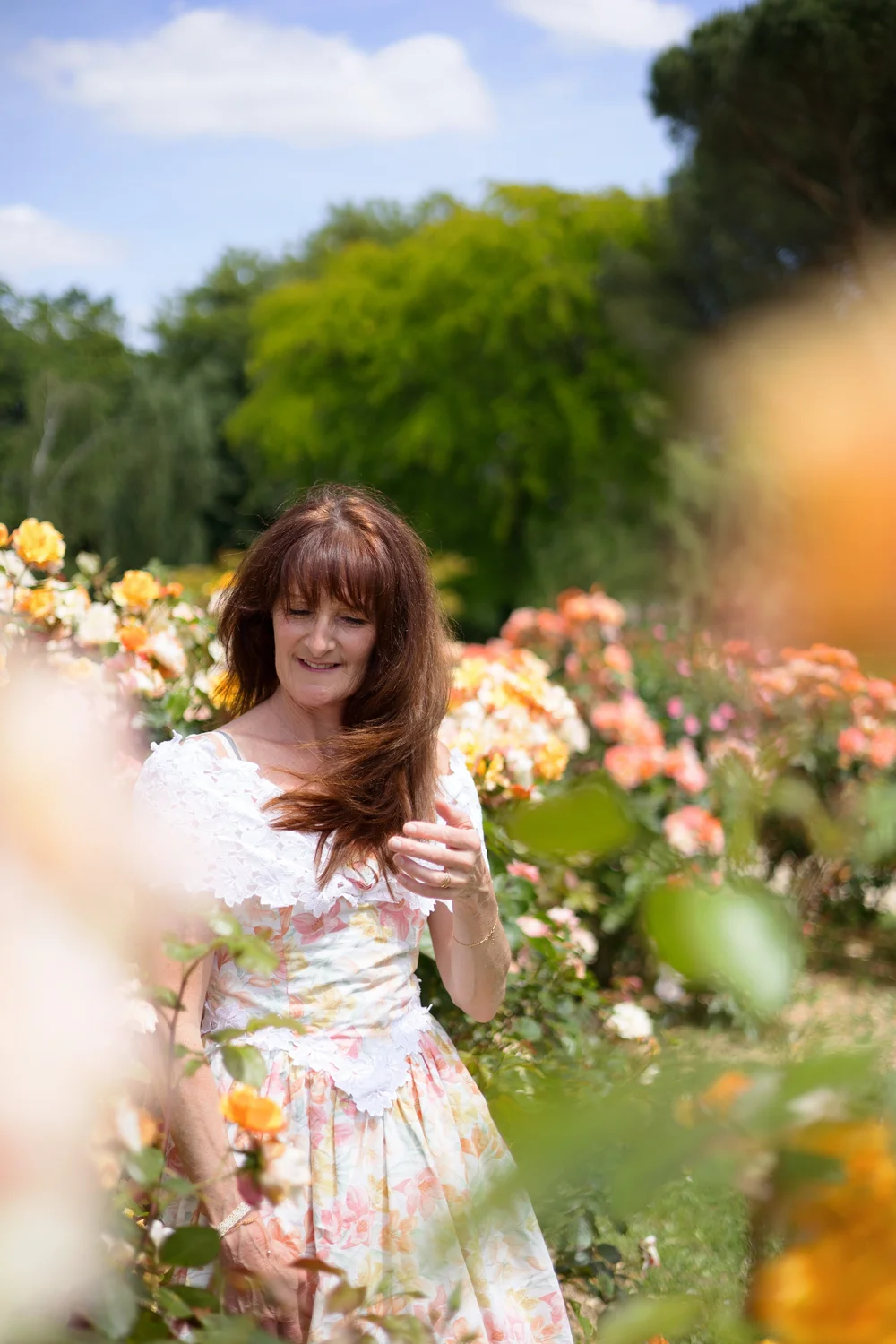 Femme en robe fleurie parmi des roses.