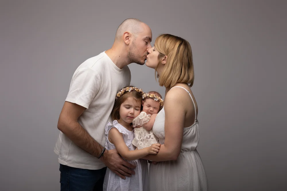 Parents s’embrassant, leurs deux enfants devant eux, en studio.
