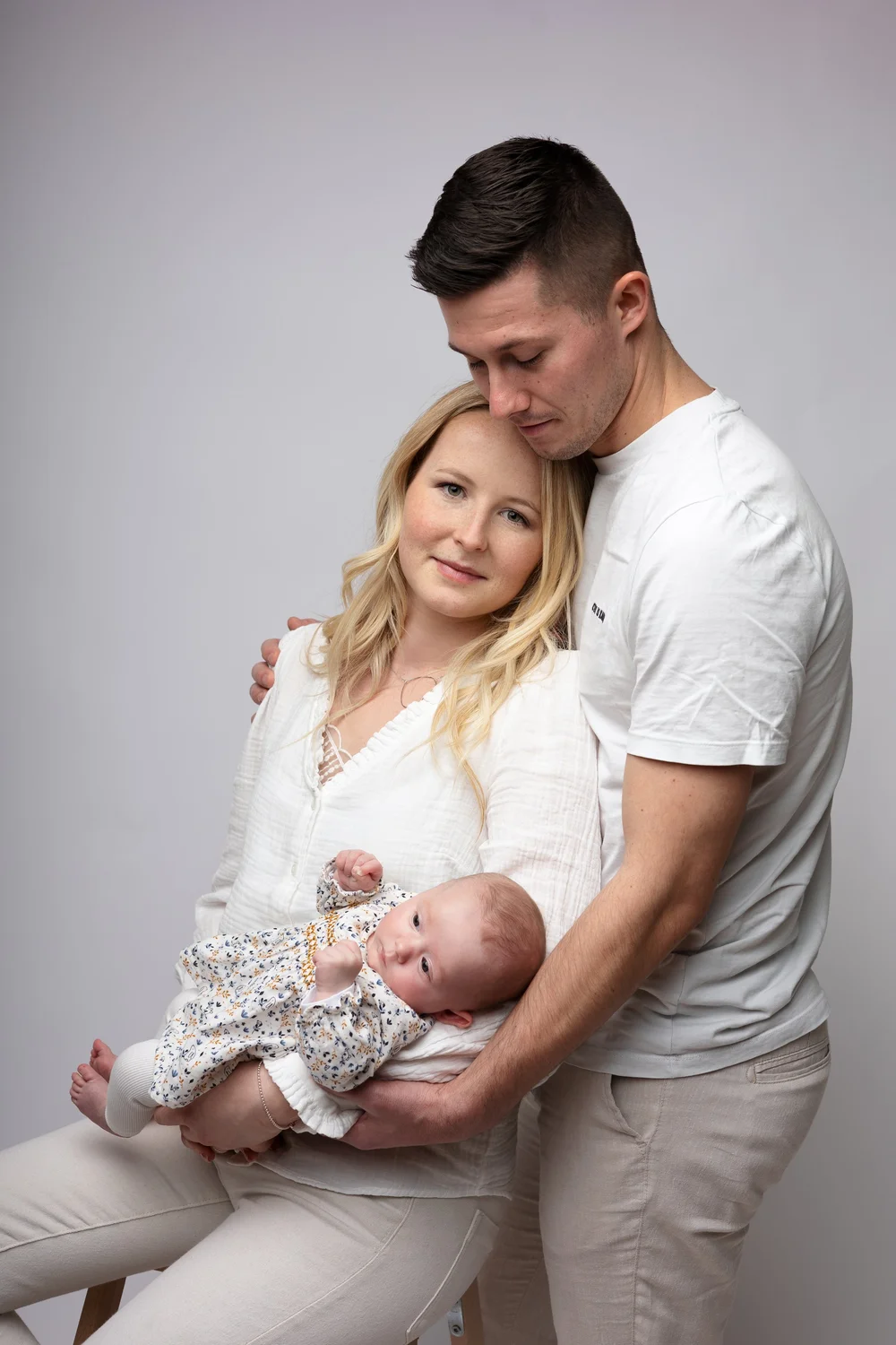 Parents en studio avec leur nouveau-né, sur fond clair.