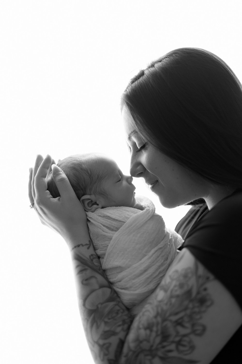 Maman nez à nez avec son nouveau-né, en noir et blanc, en contre-jour.