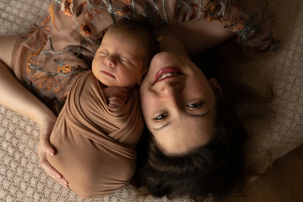 Nouveau-né emmailloté tête contre tête avec sa maman, vue de dessus.
