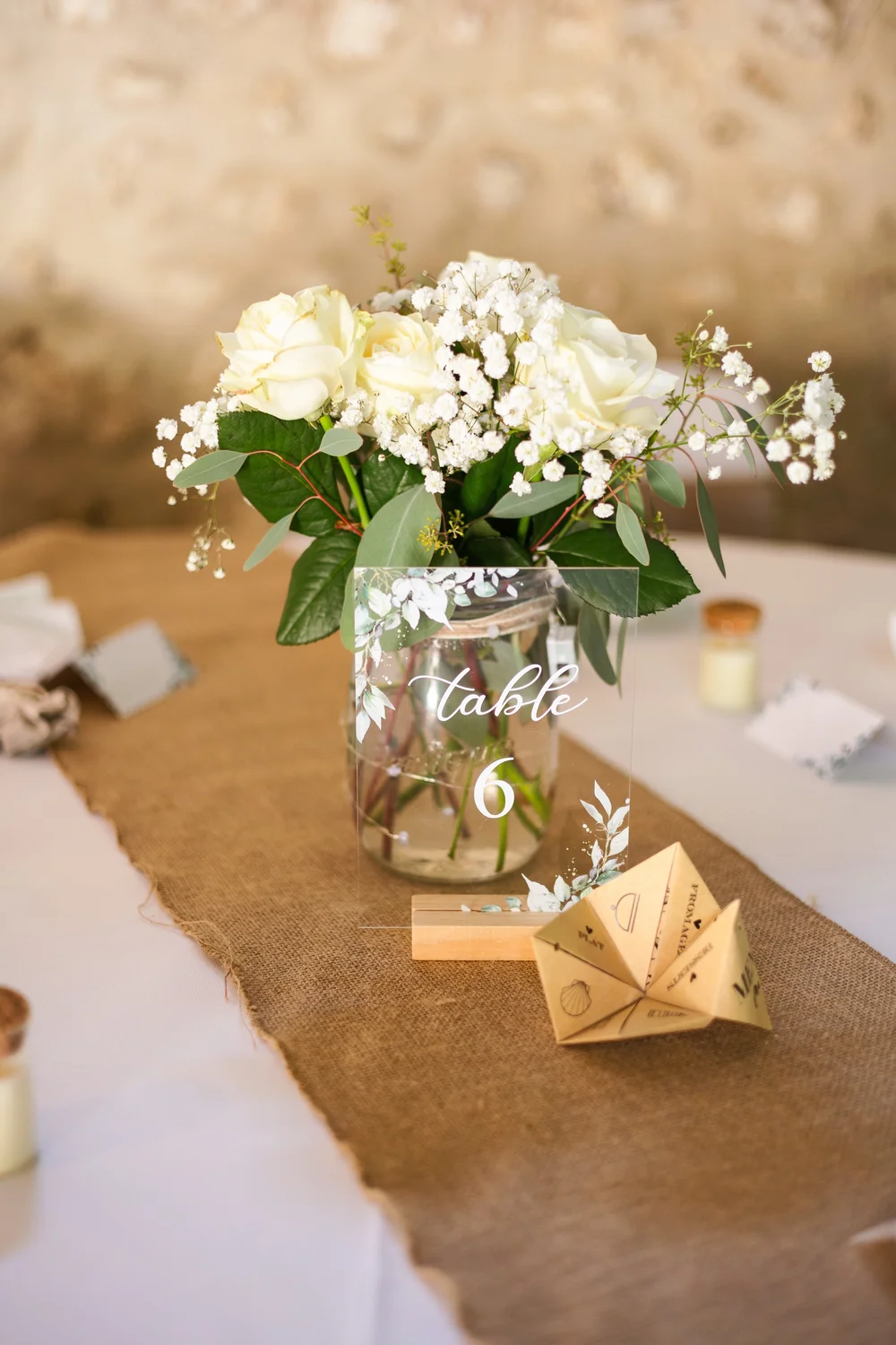 Décoration de table avec fleurs blanches dans un bocal.