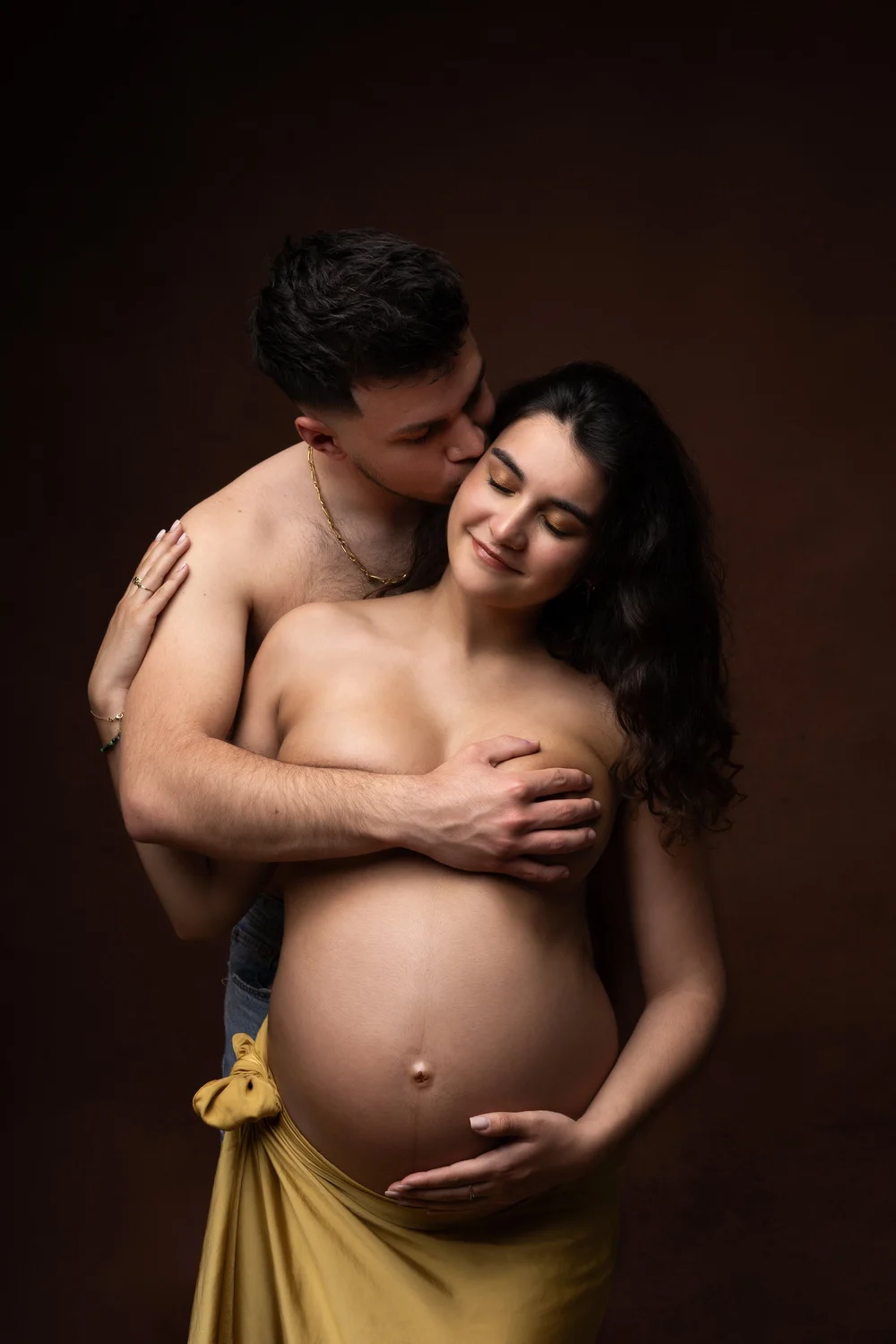 Couple enlacé en studio, drapé jaune, sur fond brun.
