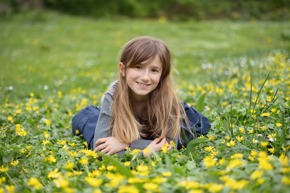 Fillette allongée dans un champ de fleurs jaunes.
