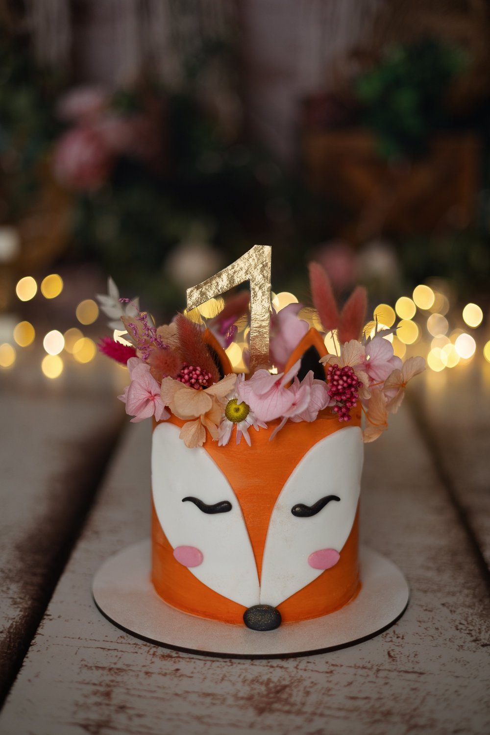 Gâteau d’anniversaire renard avec une bougie « 1 » et des fleurs.