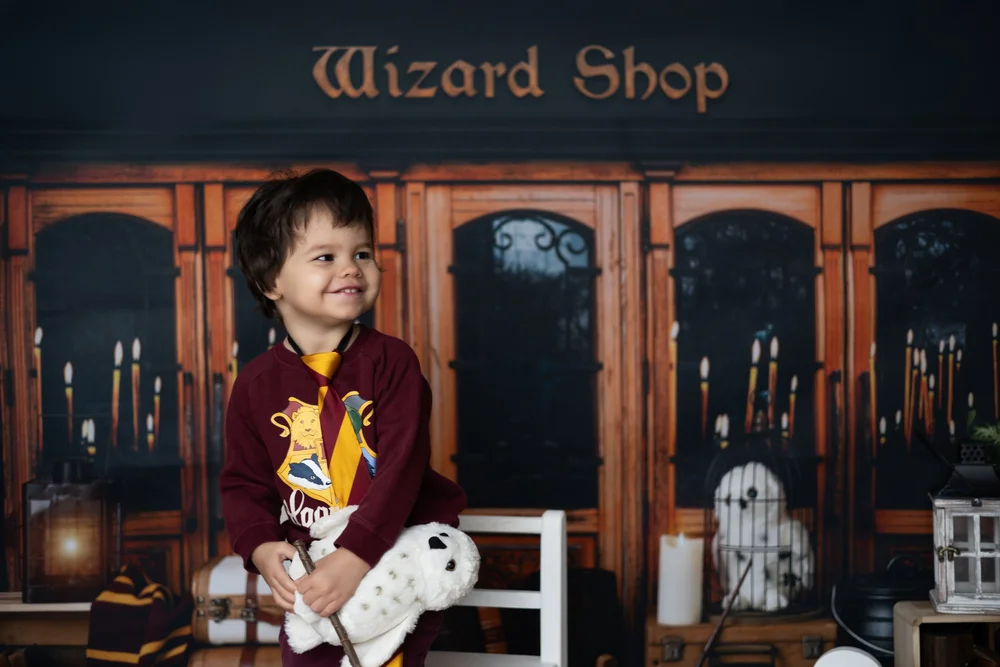 Petit garçon devant un décor de boutique de magicien.