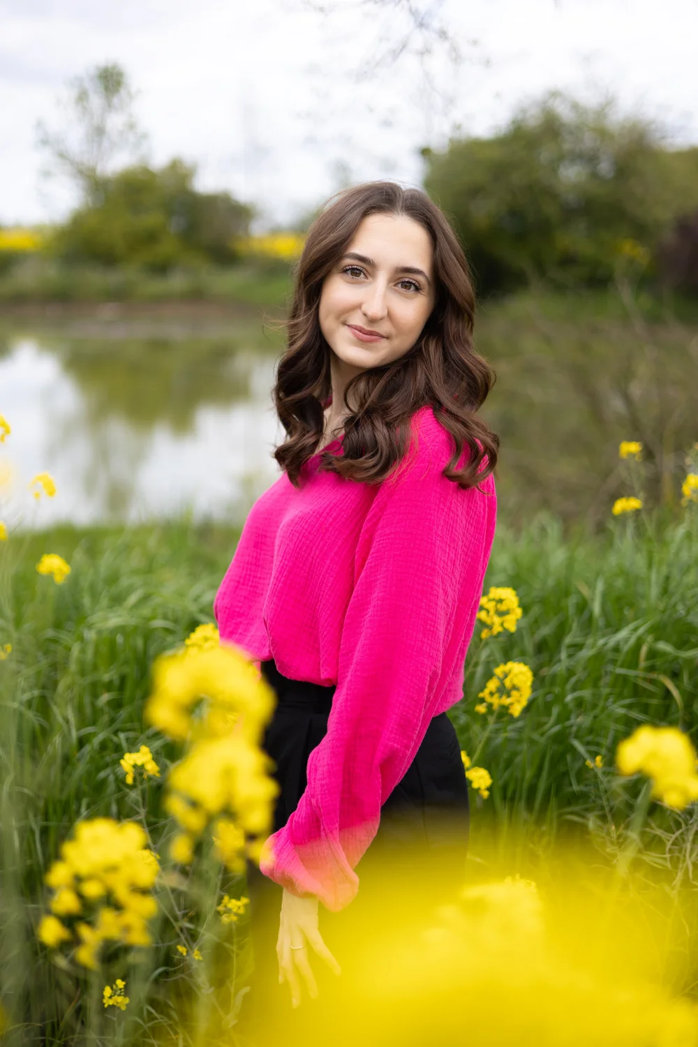 Femme en pull rose vif dans un champ de colza.