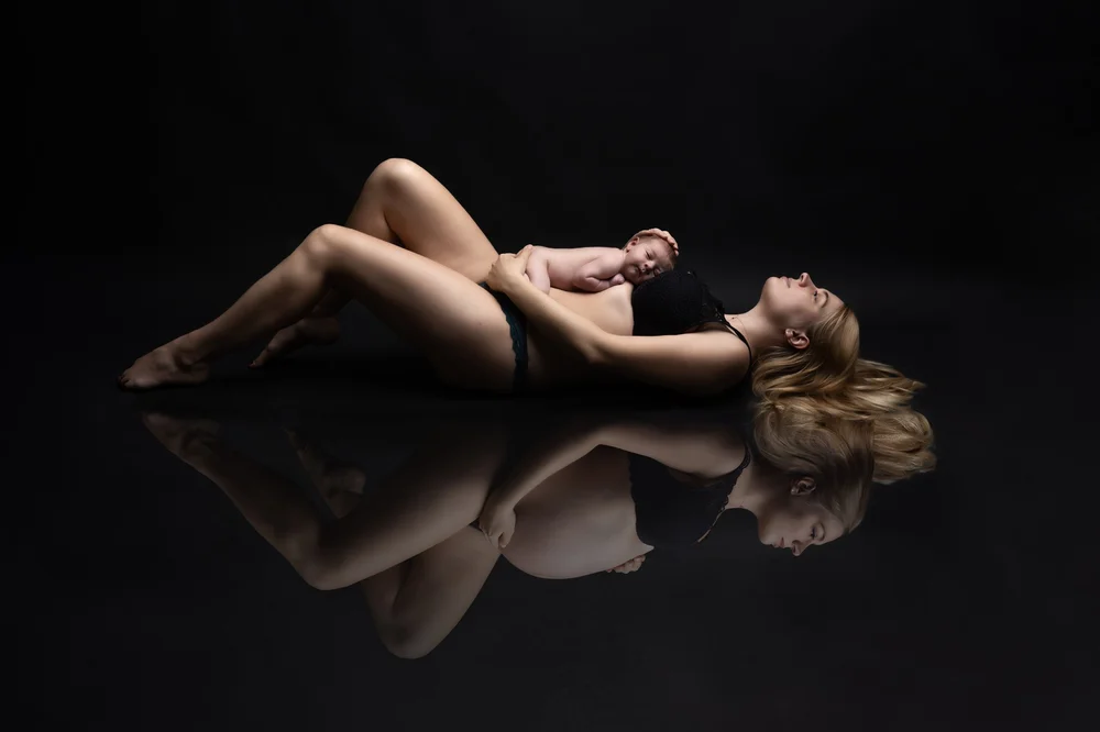 Femme allongée avec son reflet, sur fond noir.