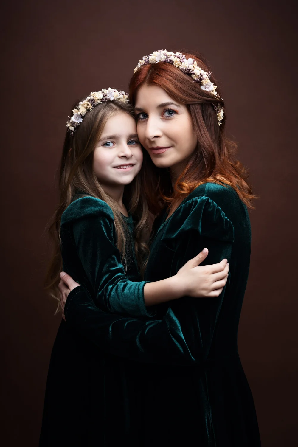Mère et fille en velours vert, couronnes de fleurs, sur fond brun.