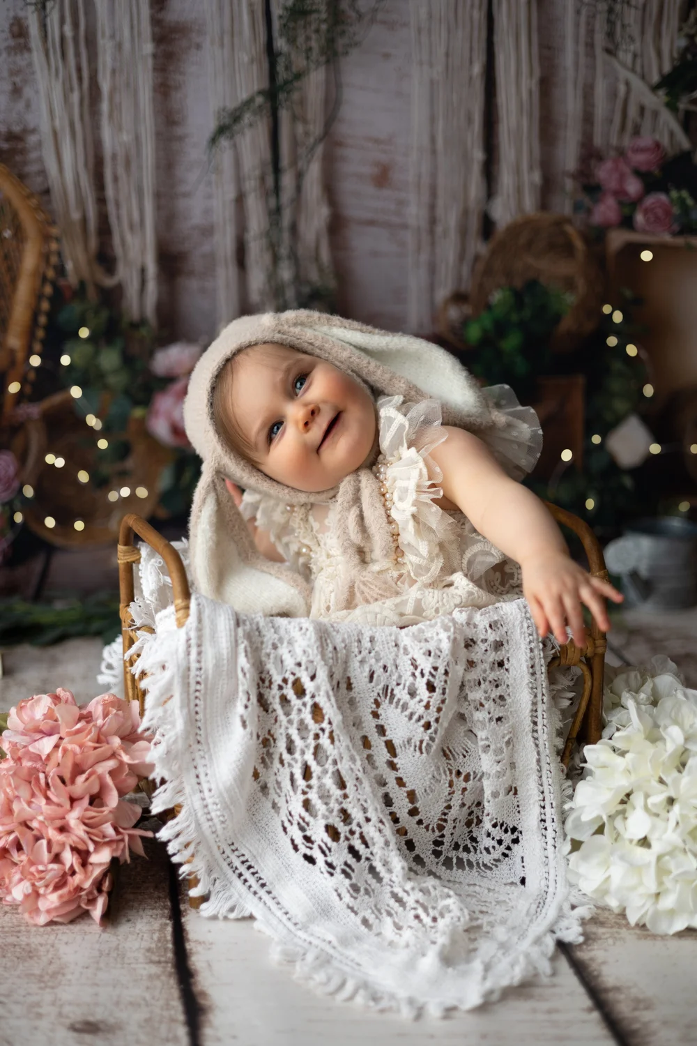 Bébé en bonnet de dentelle dans un panier fleuri.
