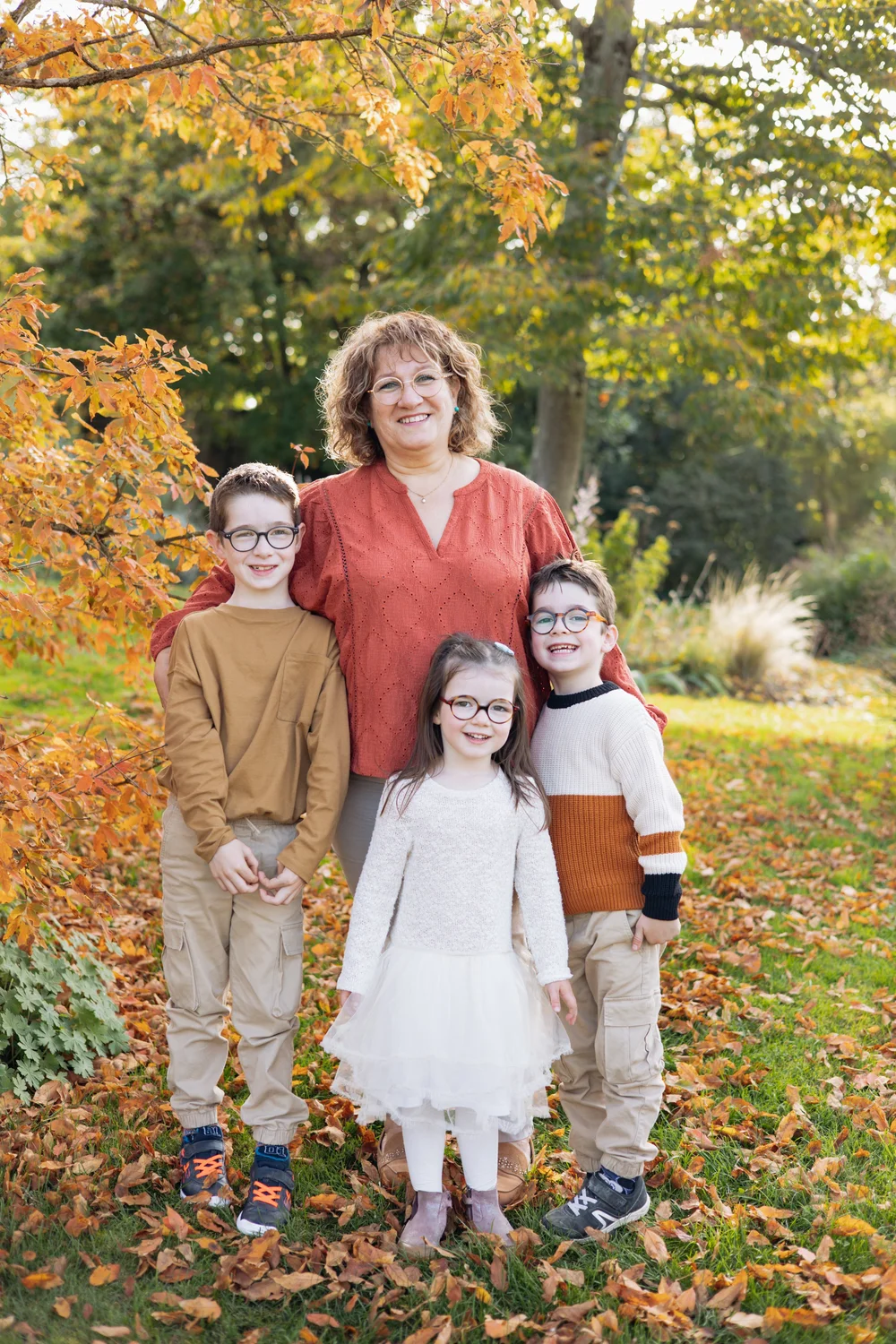 Grand-mère et ses trois petits-enfants dans un parc aux feuilles d’automne.
