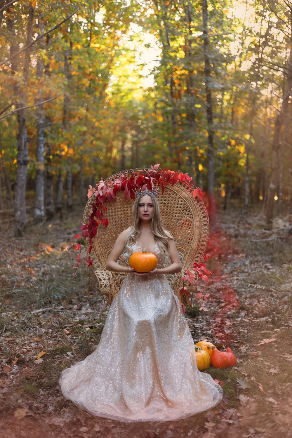 Femme en robe blanche dans un fauteuil en rotin en forêt, décor d’automne.