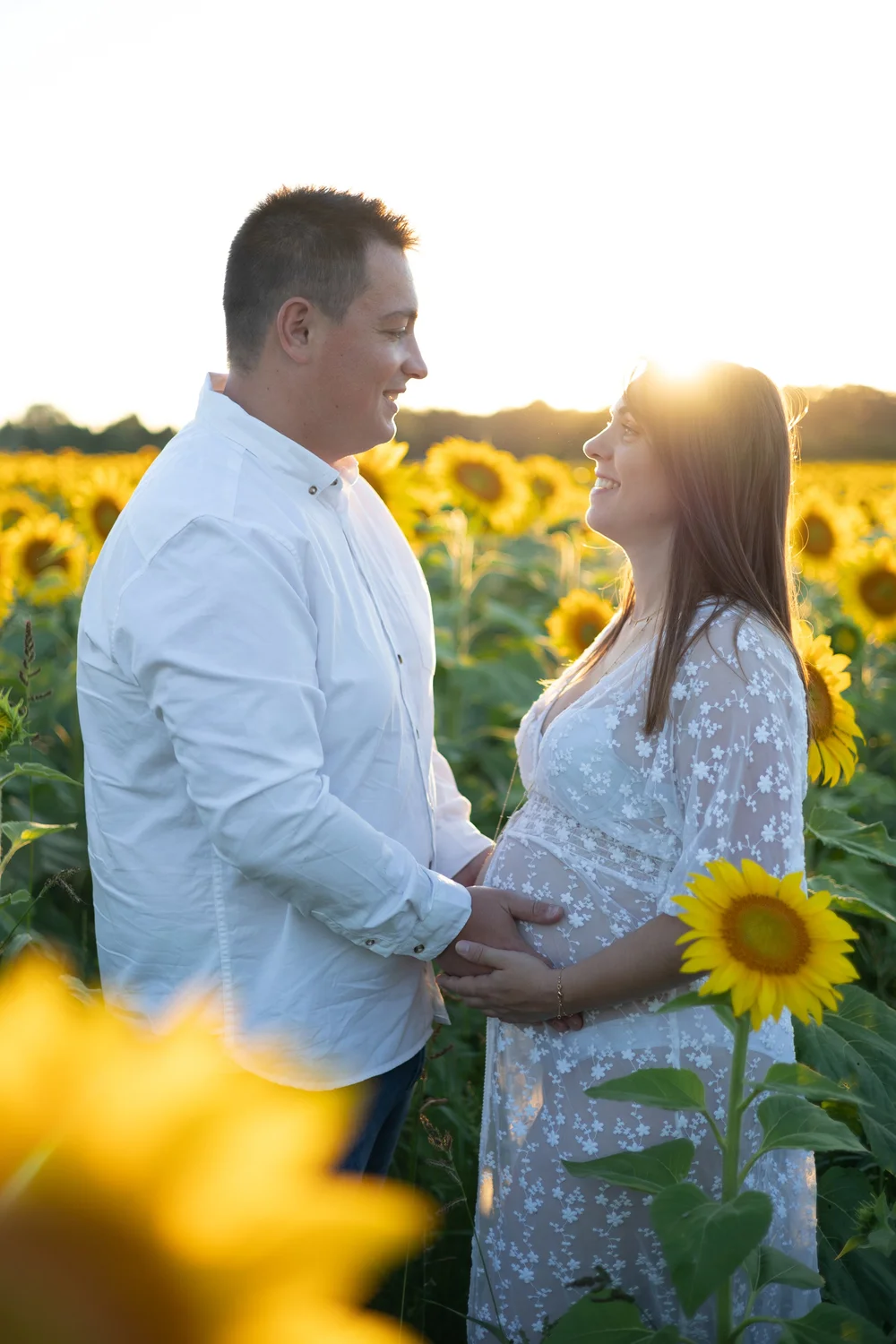 Couple dans un champ de tournesols au soleil couchant.
