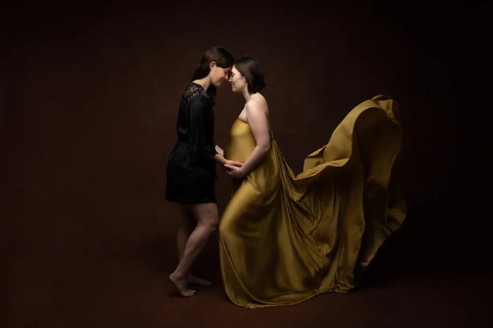 Couple en studio, la femme enceinte en robe jaune moutarde qui vole.