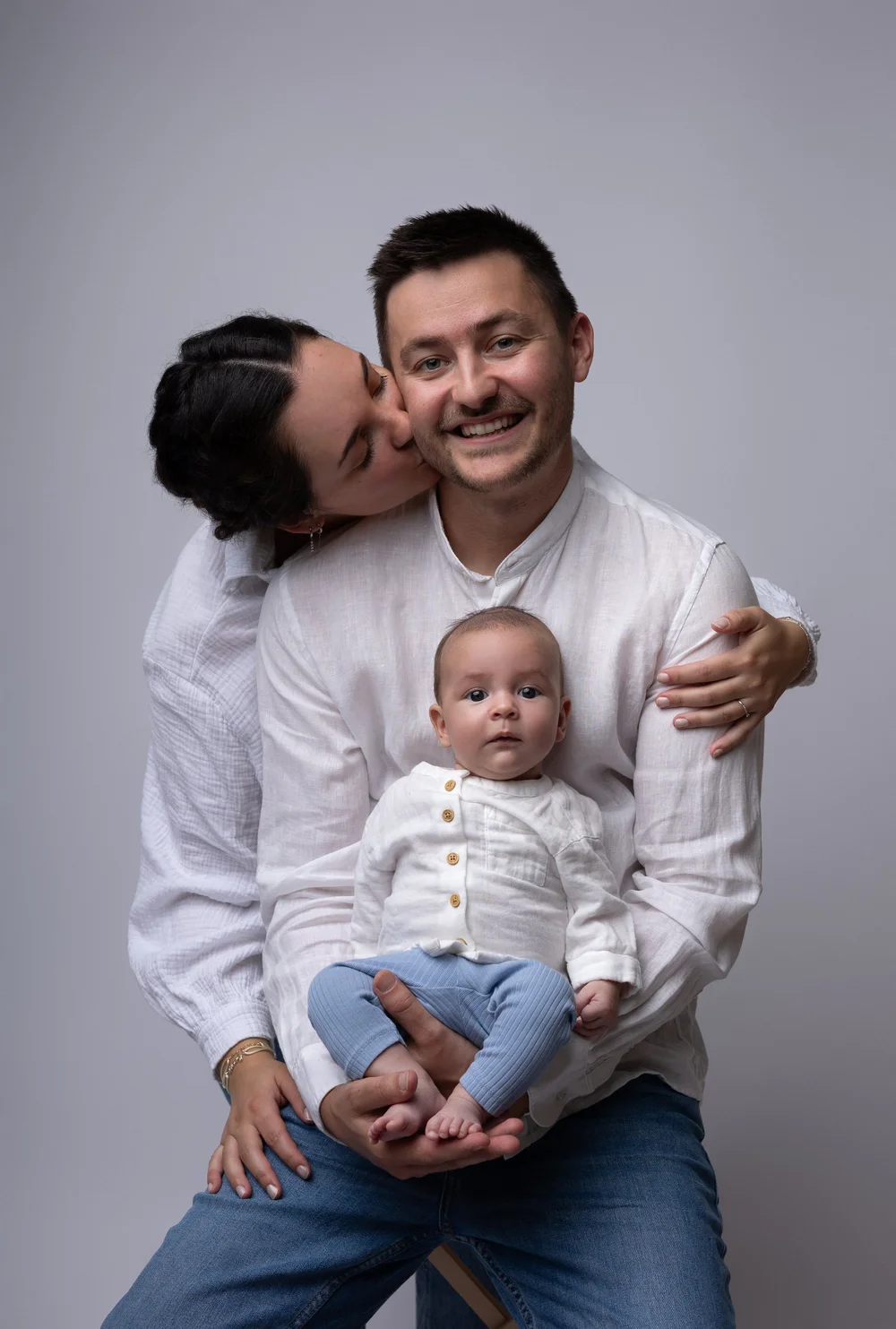 Deux mamans et leur bébé en studio, sur fond gris.