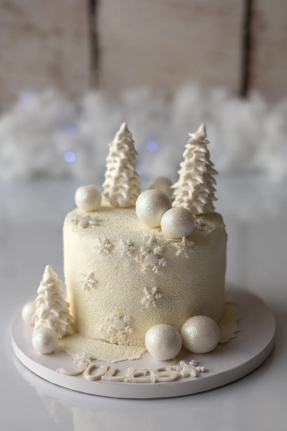 Gâteau blanc d’hiver décoré de sapins et de boules.