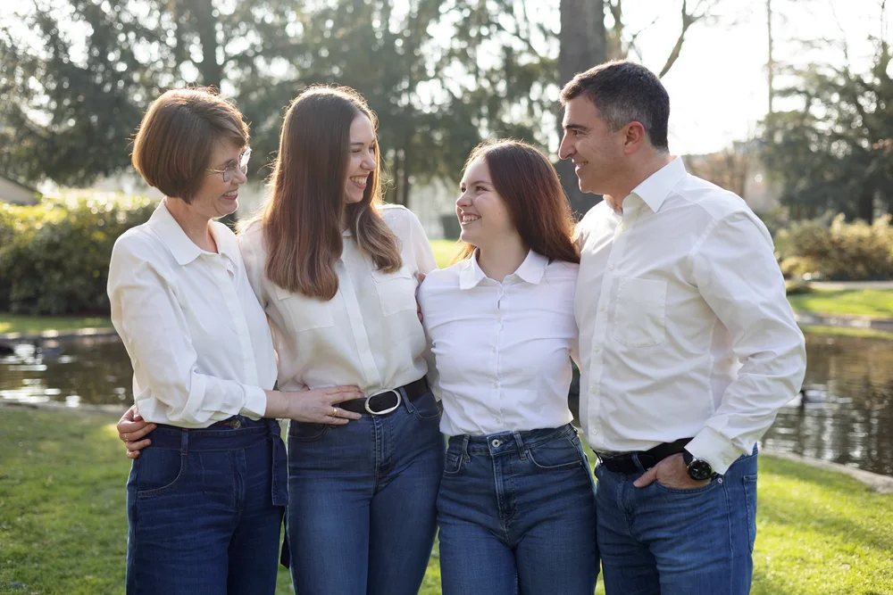 Famille de quatre en chemises blanches dans un parc.