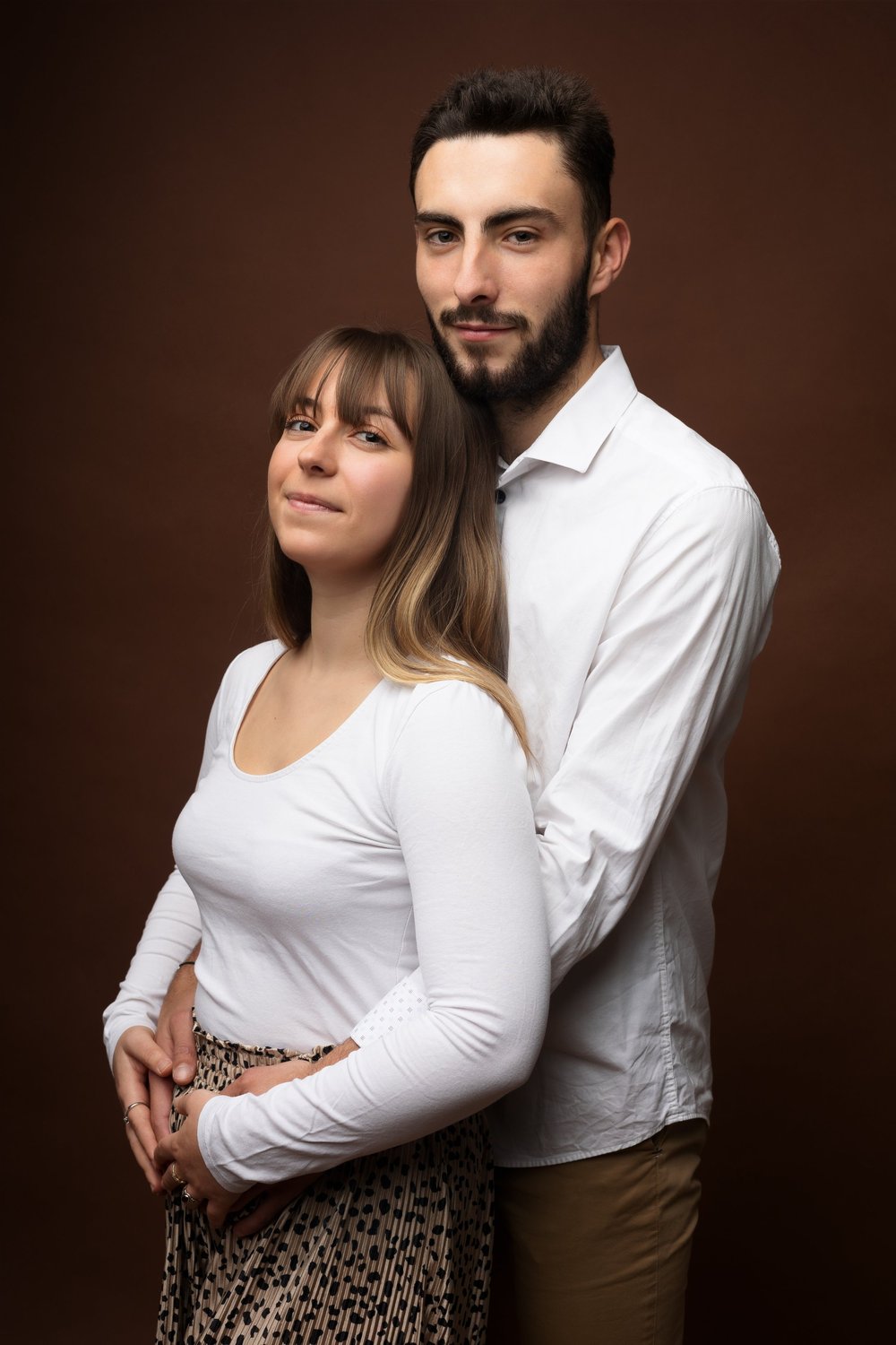 Couple enlacé en studio, sur fond brun.