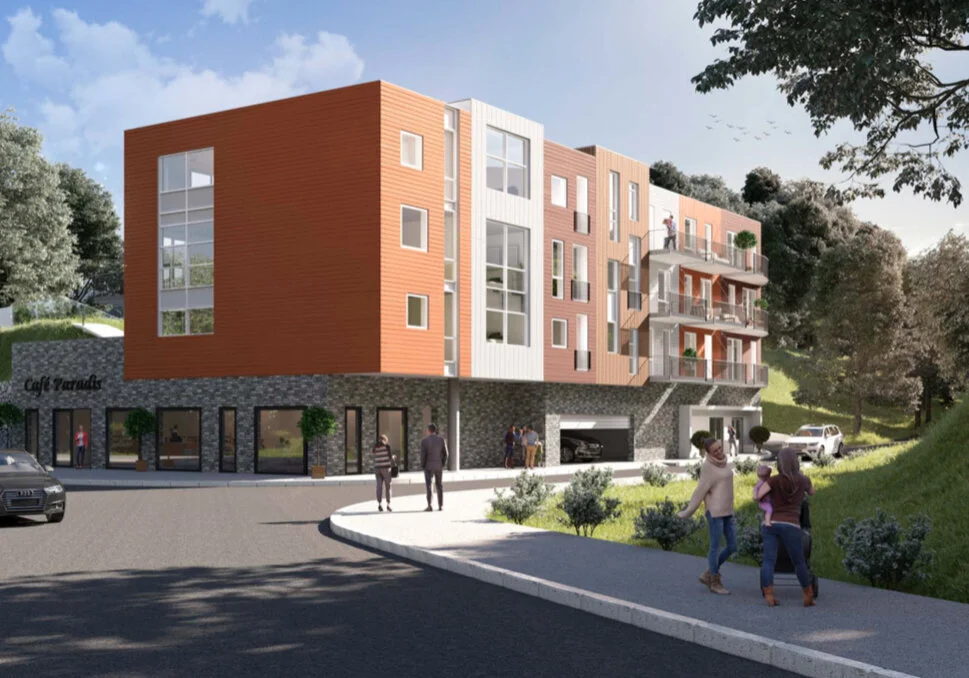 Moderne boligbygg med trepanel og steinfasade, flere etasjer og balkonger. Mennesker går på fortauet og bilen står parkert på veien. Trær og grøntområder omgir bygningen under en blå himmel.