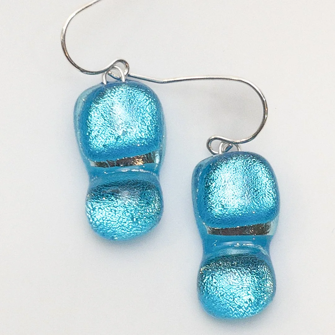 A pair of handcrafted Splash! fused dichroic glass earrings in vibrant ocean blue, set on sterling silver hooks.