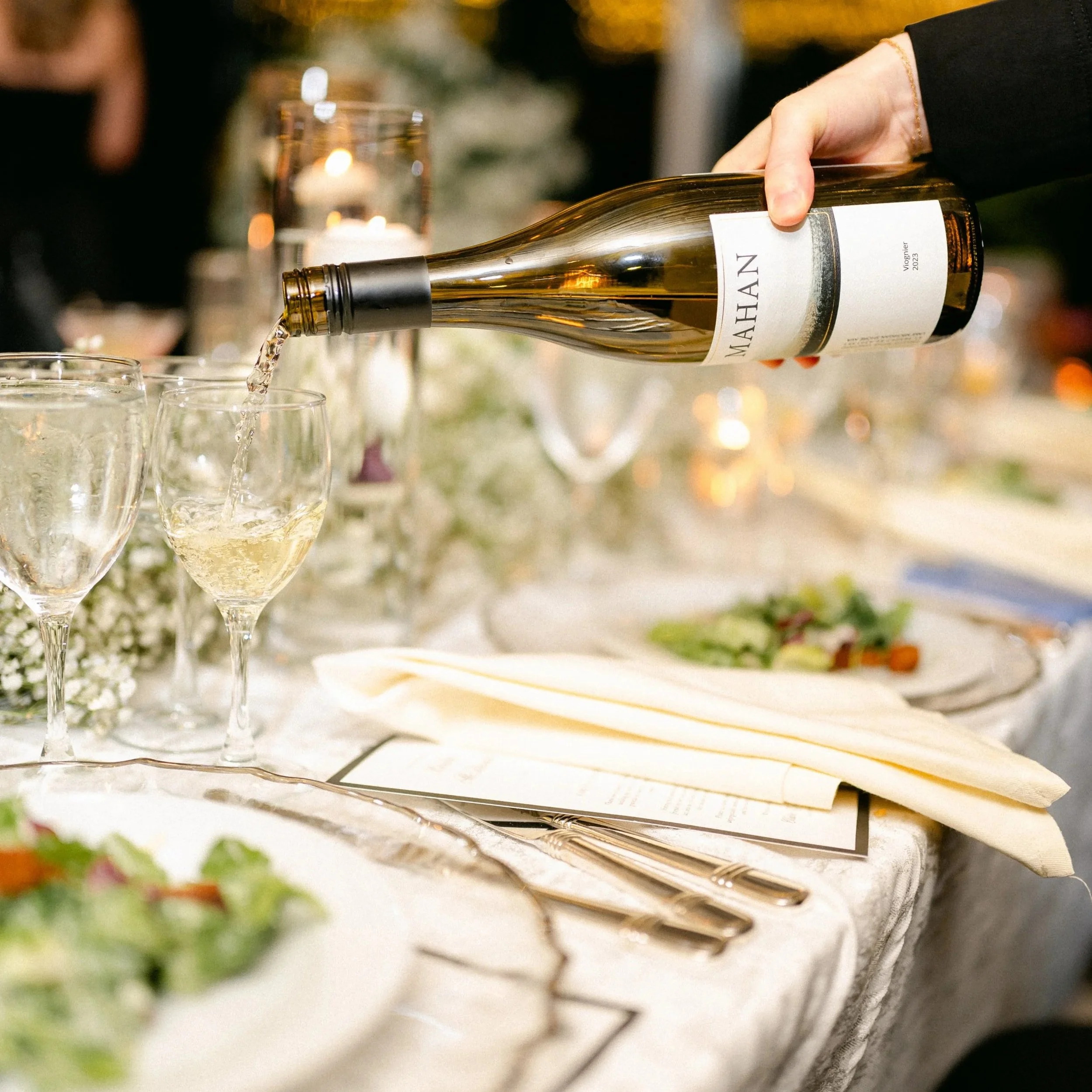 White wine being poured at a formally set table, reflecting Mahan Family Wines’ vintage-over-vintage winemaking philosophy and consistent quality