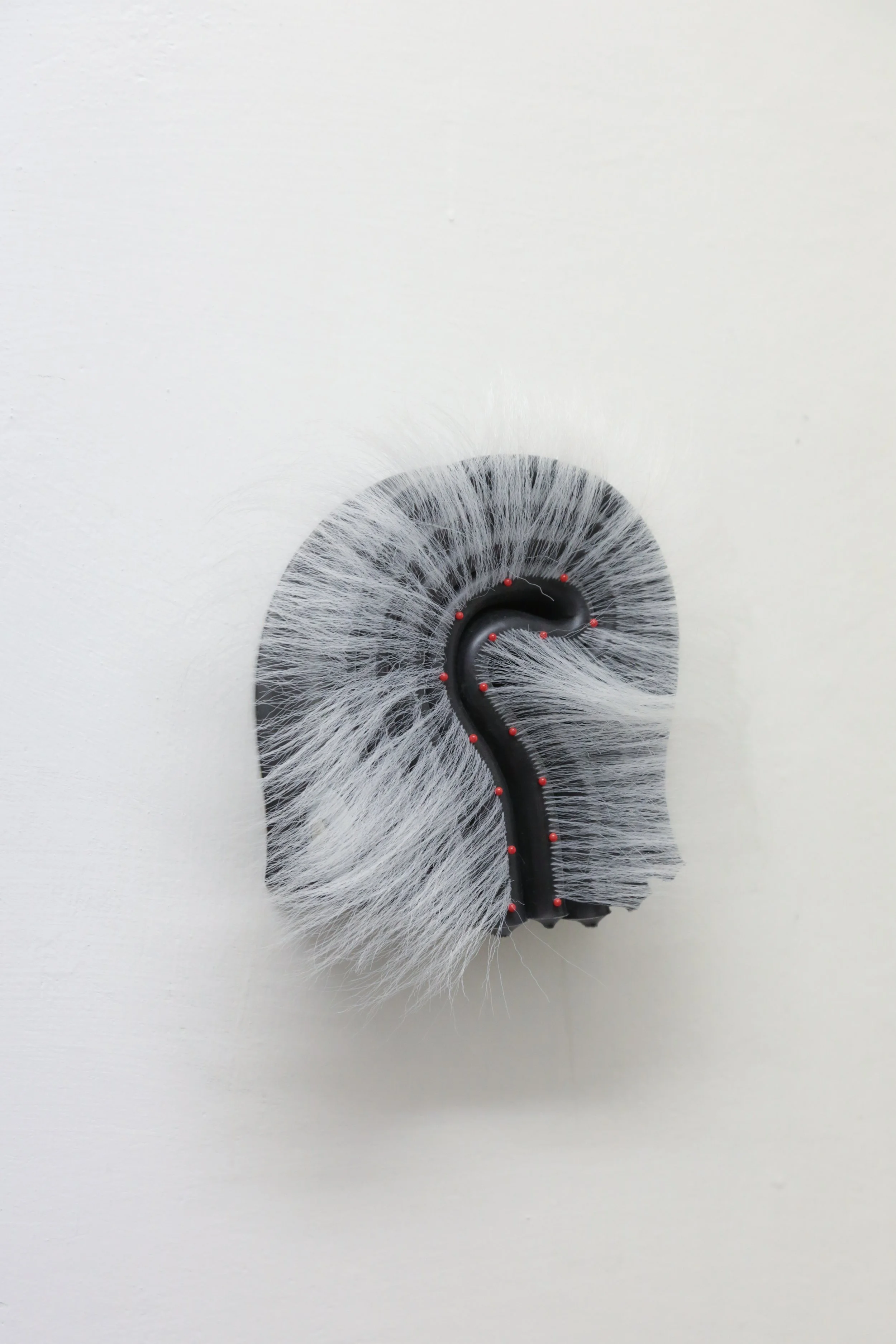 fig24  Marlie Mul,  Unnamed Charm , 2024, Silicone, pin with glass, head, synthetic hair, stainless steel hardware, Unique. 9 x 8 x 3.4 inches