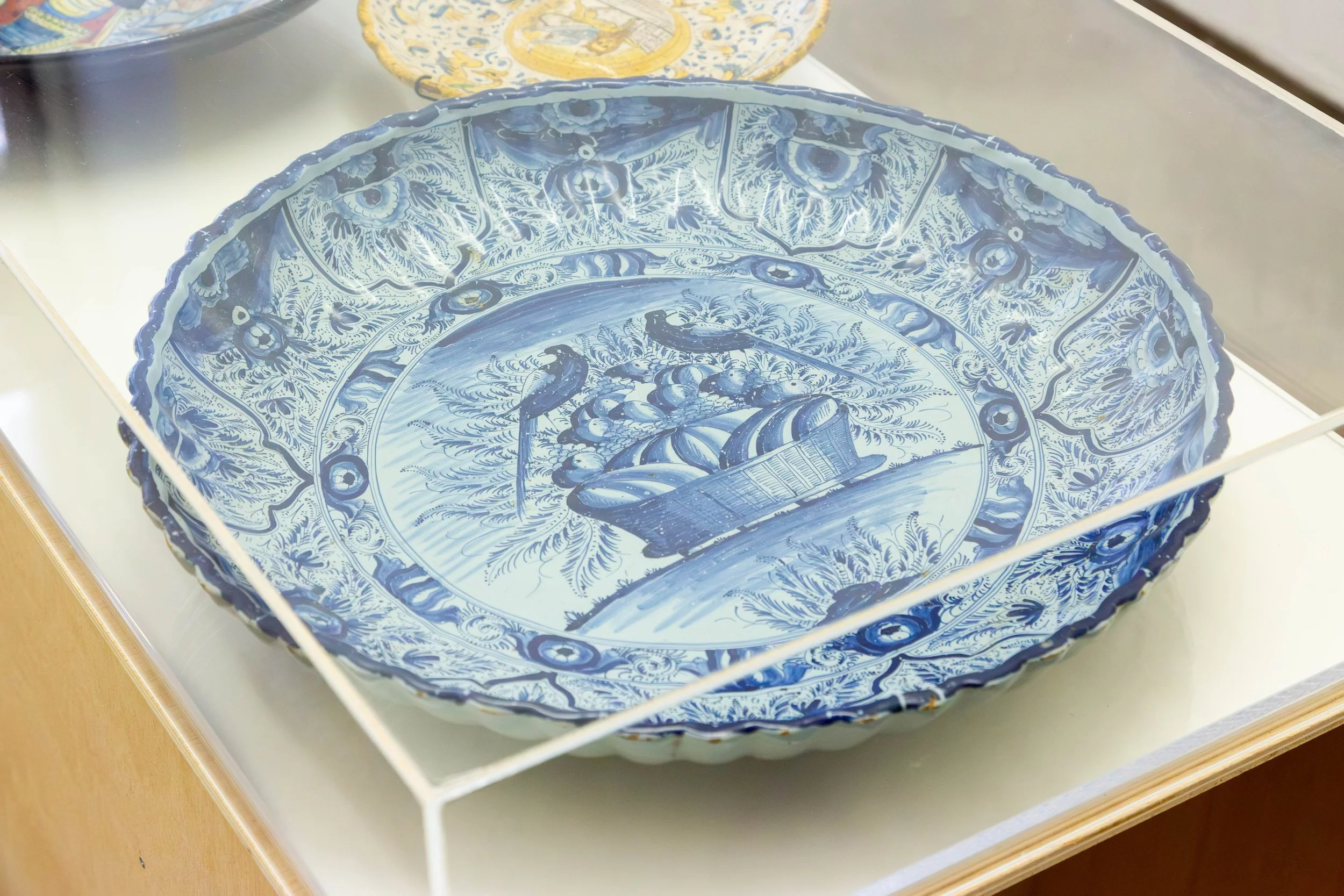   fig36   le monde , 2026, plywood, cardboard, acrylic glass, 86,5 x 125 x 50 cm, Large plate, Nuremberg, Germany, 2nd quarter of the 18th century, Faience, gadrooned rim, central field with a blue-painted fruit, basket, rim decorated with floral mot