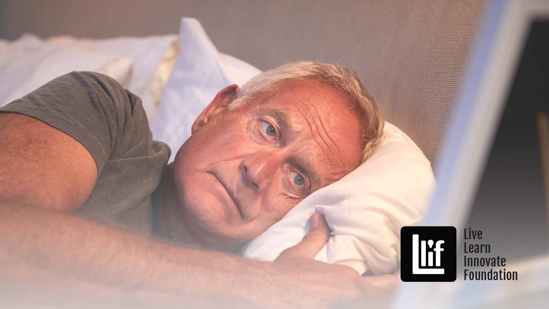 Sad Senior Man Lying In Bed Looking At Photo Frame
