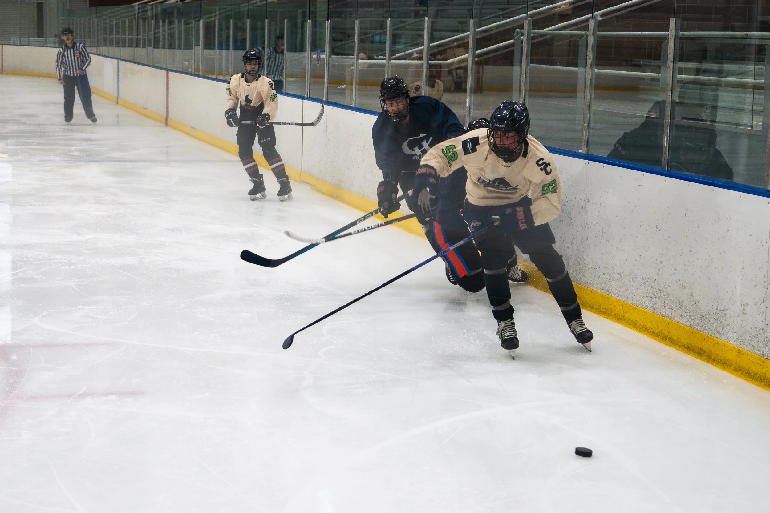 Hockey players competing for the puck along the boards during a game.