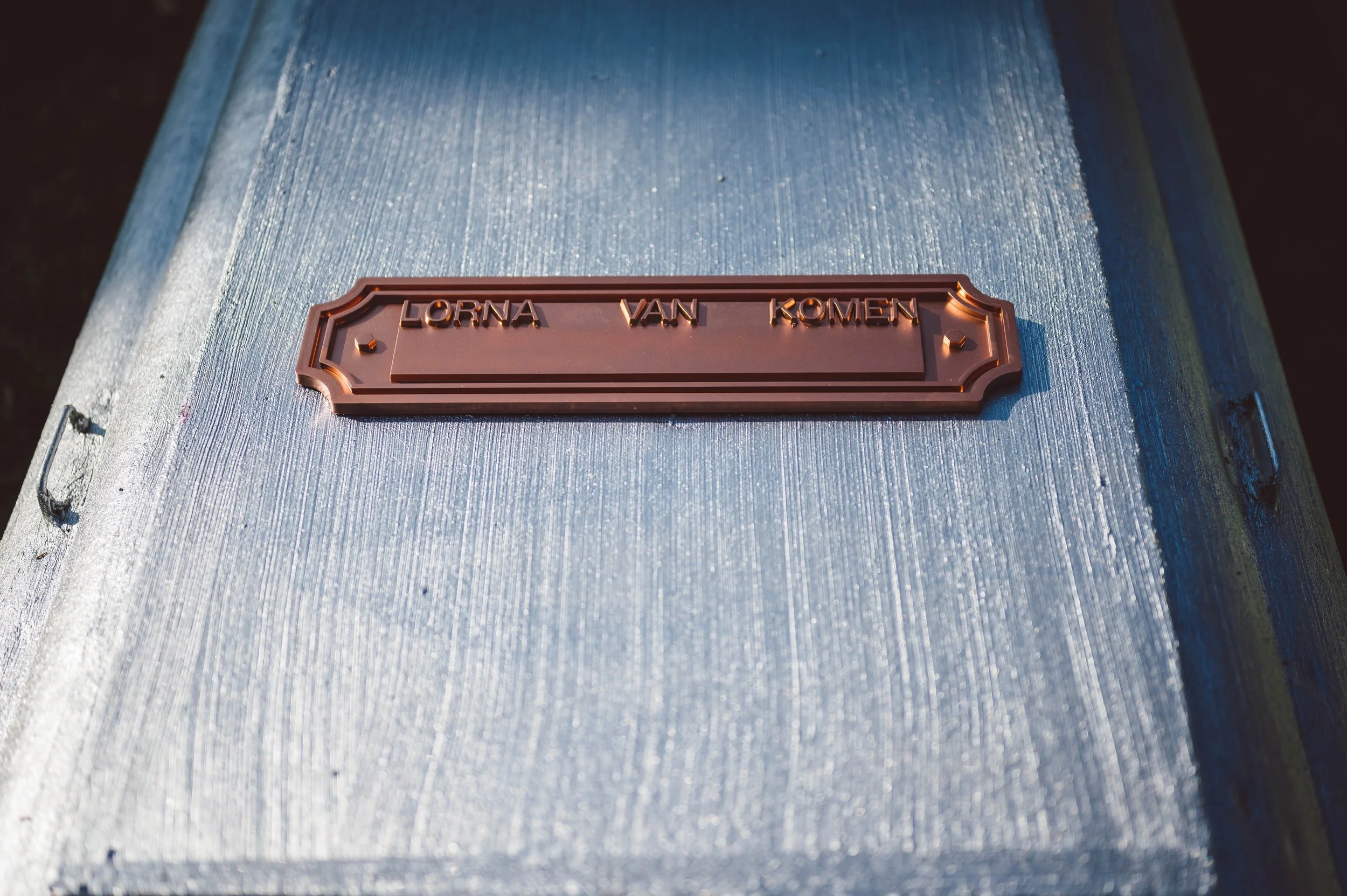 Close-up of a metallic mailbox with a nameplate reading 'LORNA VAN KOMEN'.