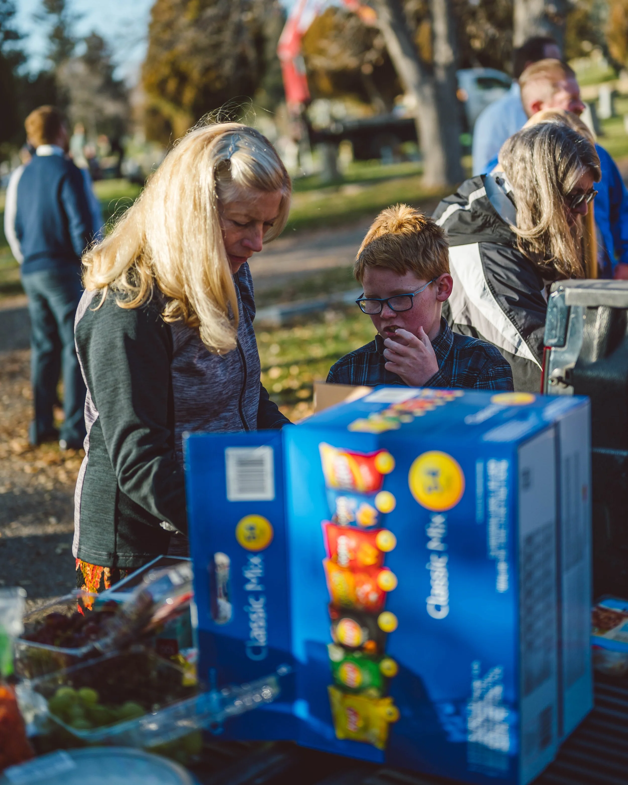People shopping outdoors with a table of snacks, including a box of Cracker Jack.