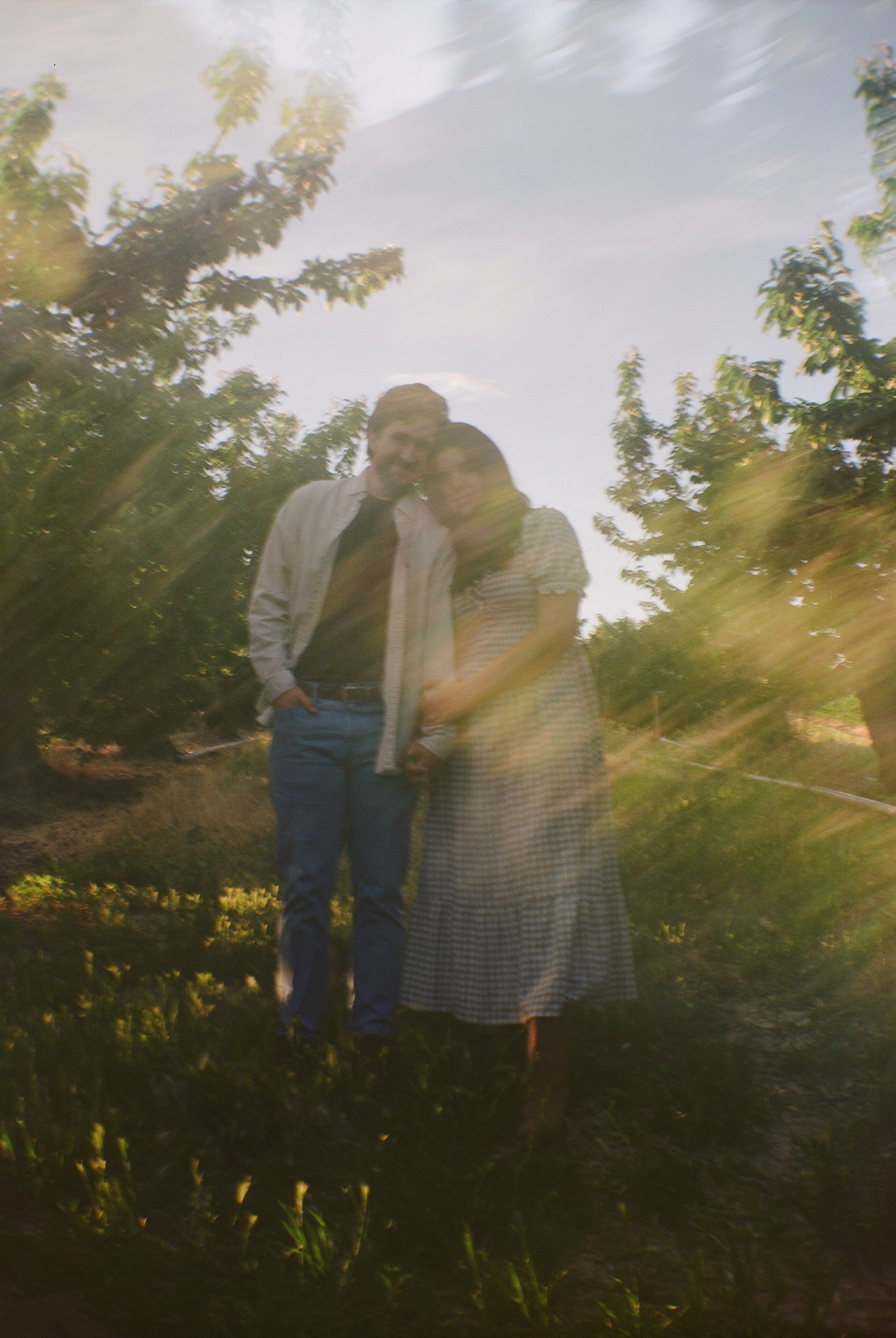 Blurry photo of a couple walking together through a sunlit garden.