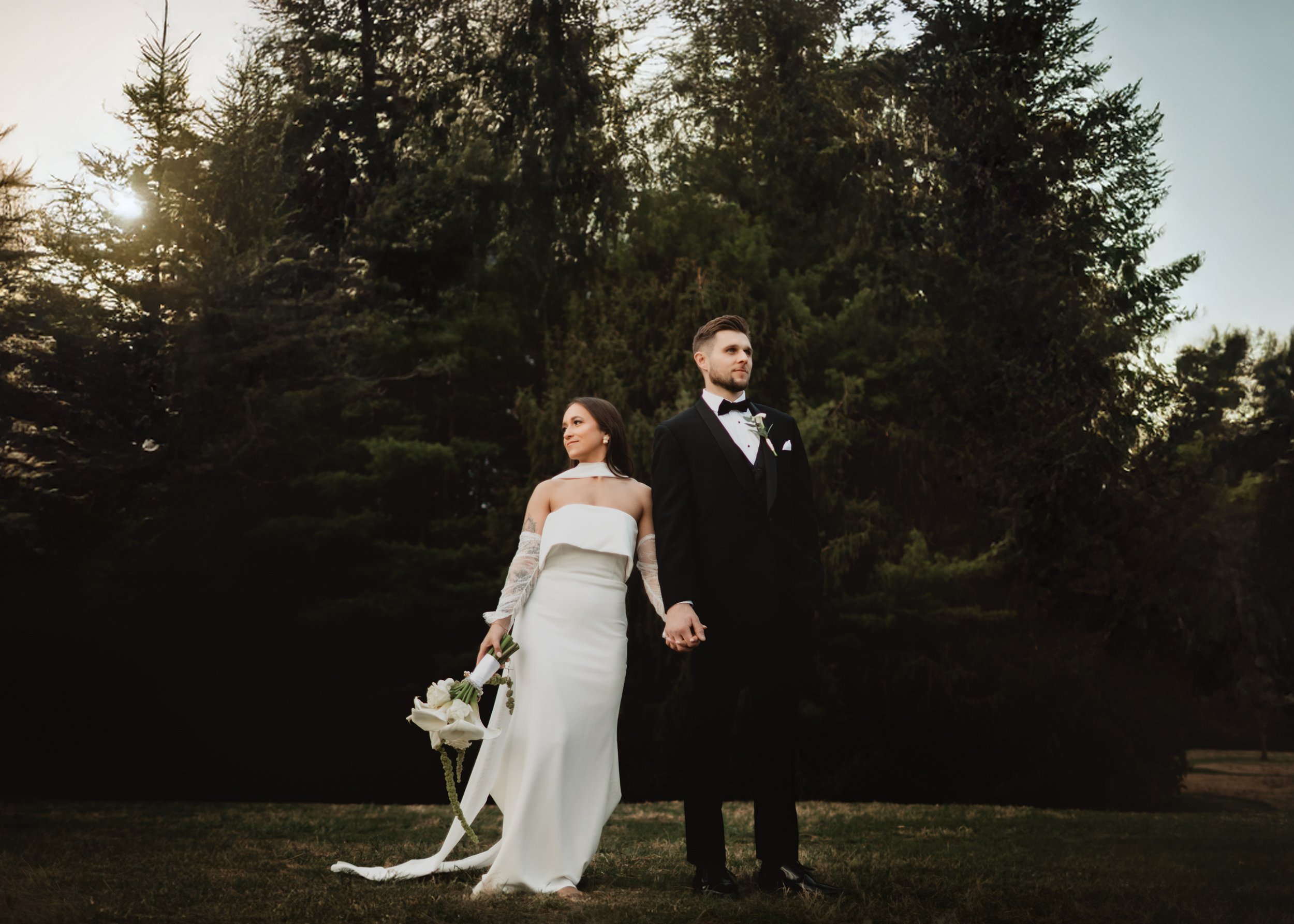 Adventure-style wedding photography at Wyomissing Park in PA, with a bride and groom walking through a lush field during the golden hour.