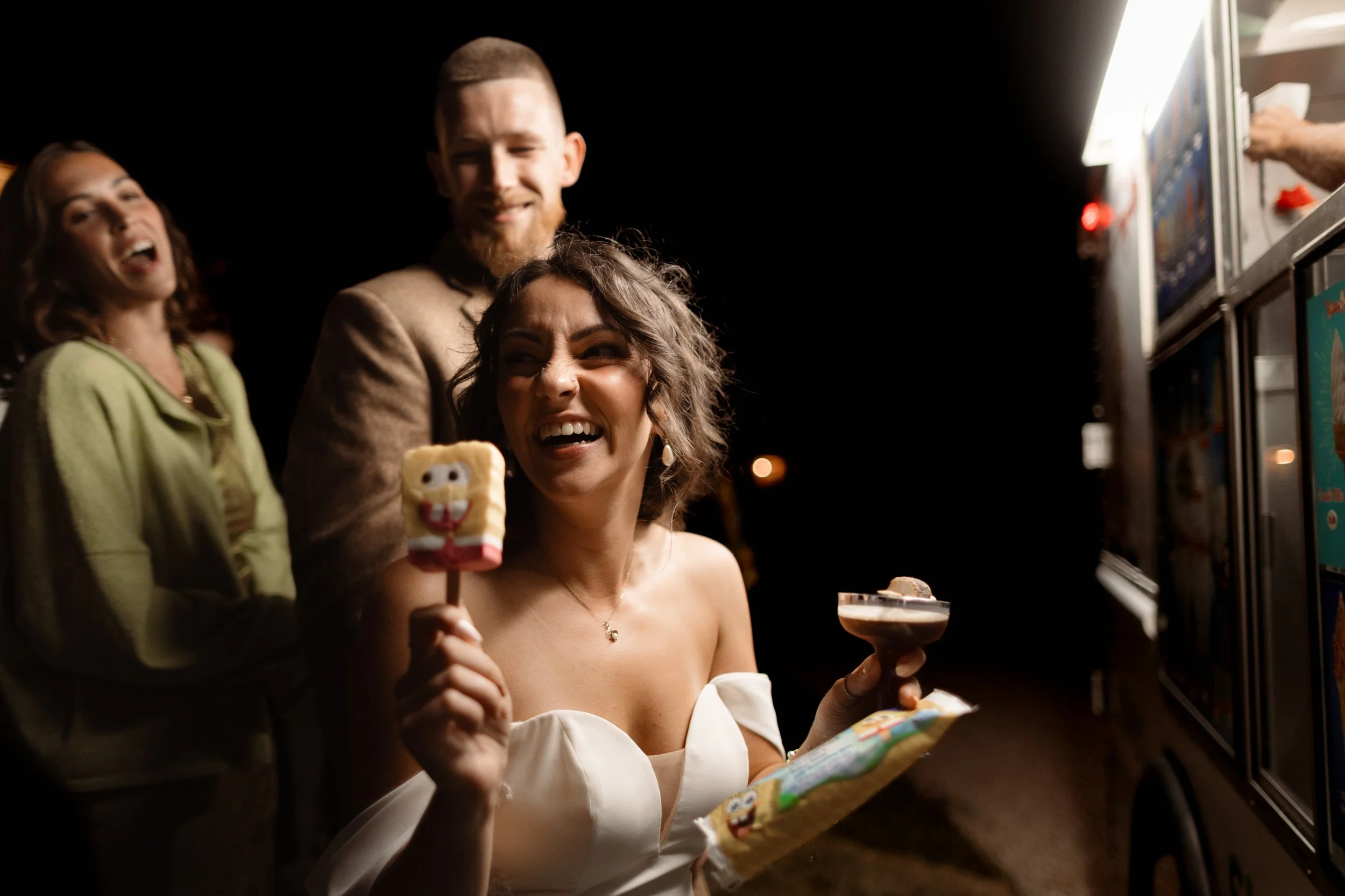 Happy bride laughing with a Spongebob popsicle and cocktail at a fun wedding reception in Berks County, PA.