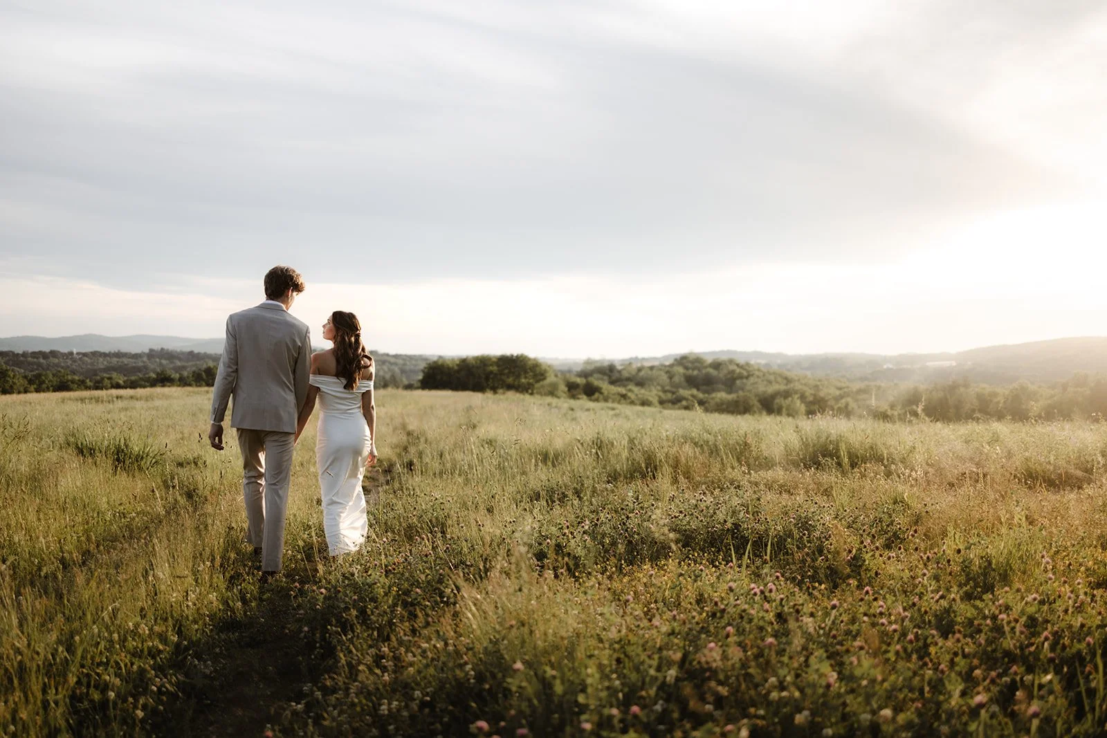 Bride and groom walking through a golden meadow at sunset during a Lancaster County micro wedding.