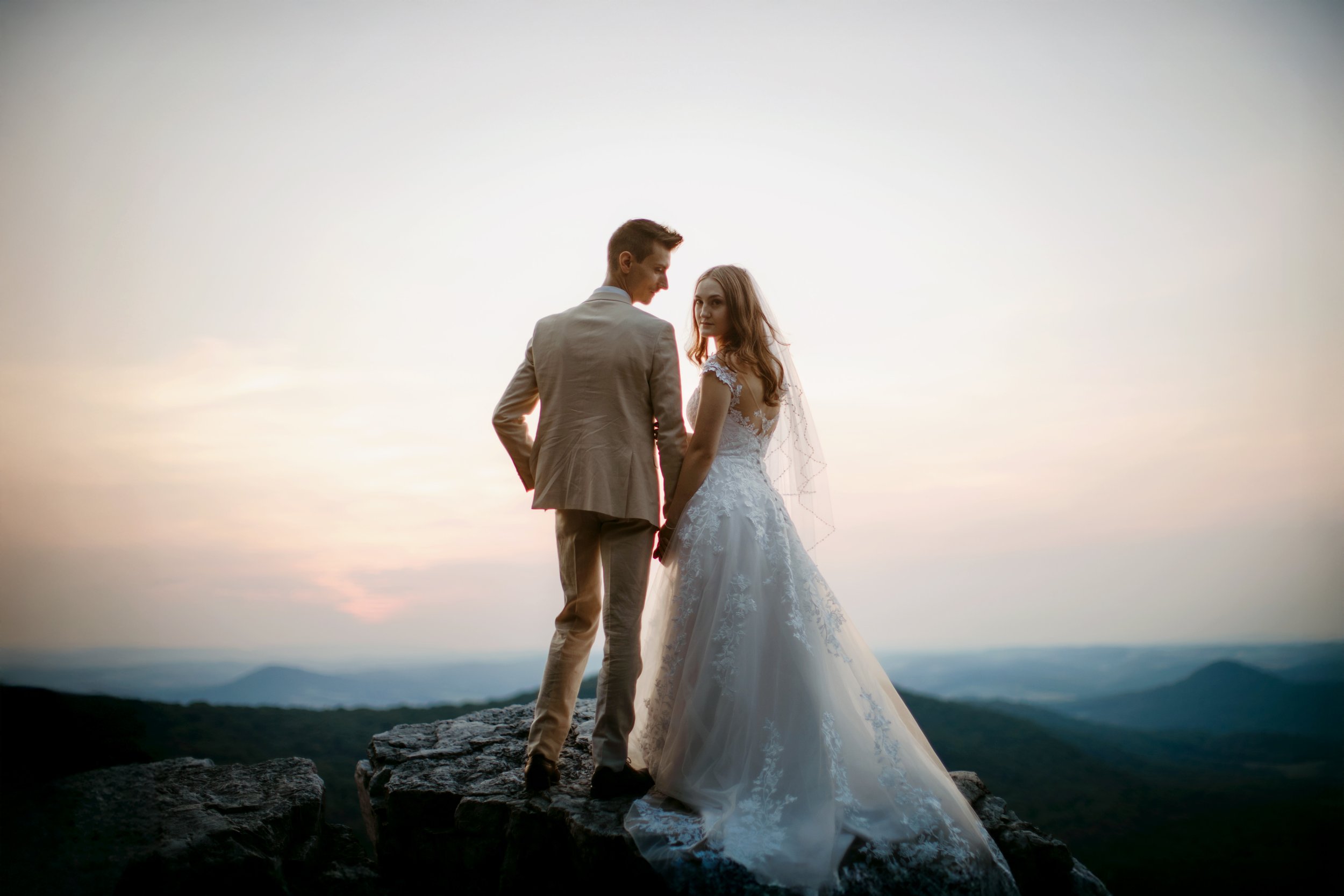Bride and groom embracing on a mountain peak at sunrise during a Berks County PA elopement