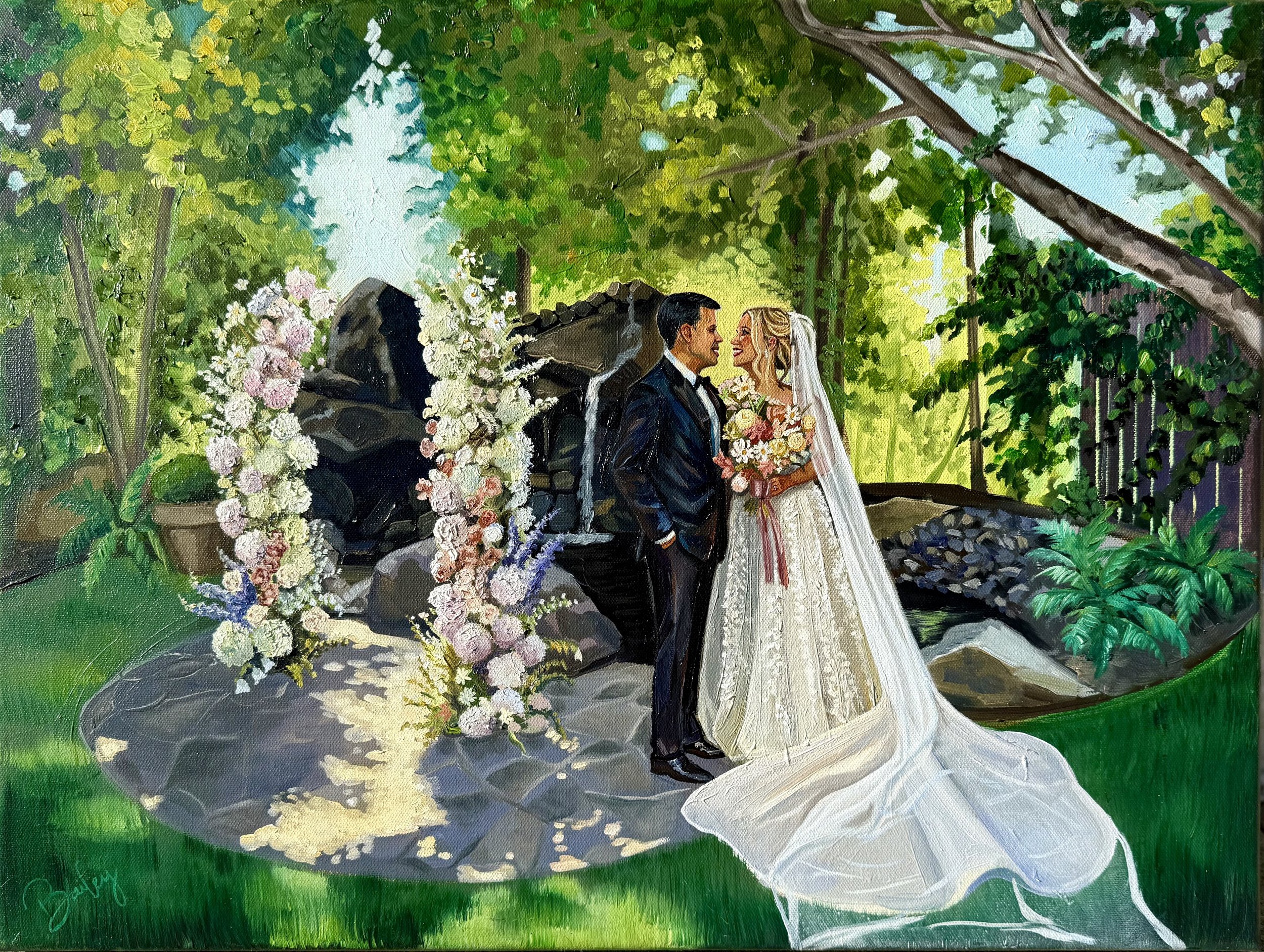 A bride and groom on their wedding day, standing in a lush green garden near a waterfall, decorated with flowers.
