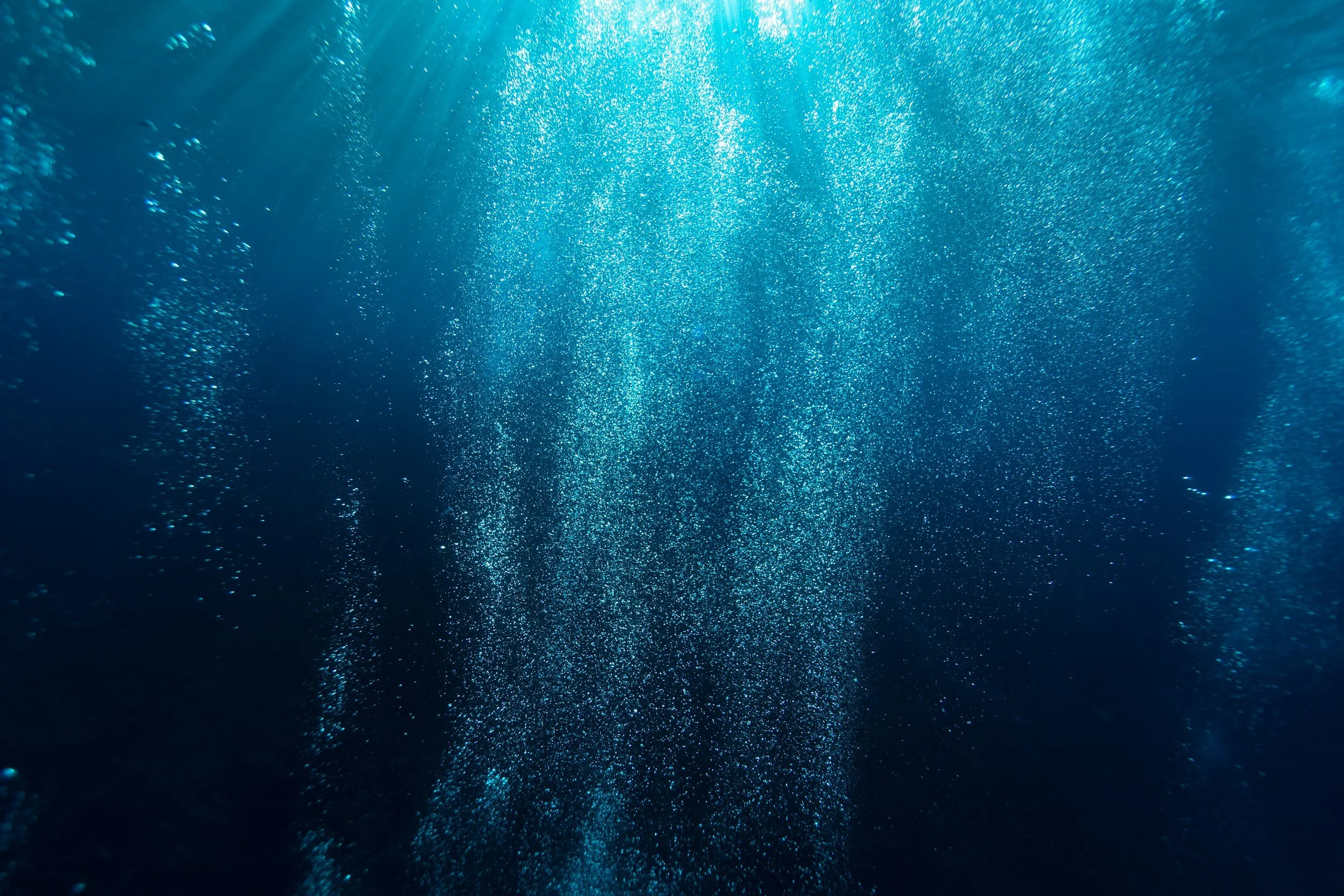 Underwater scene with sunlight streaming through the water and bubbles rising to the surface.