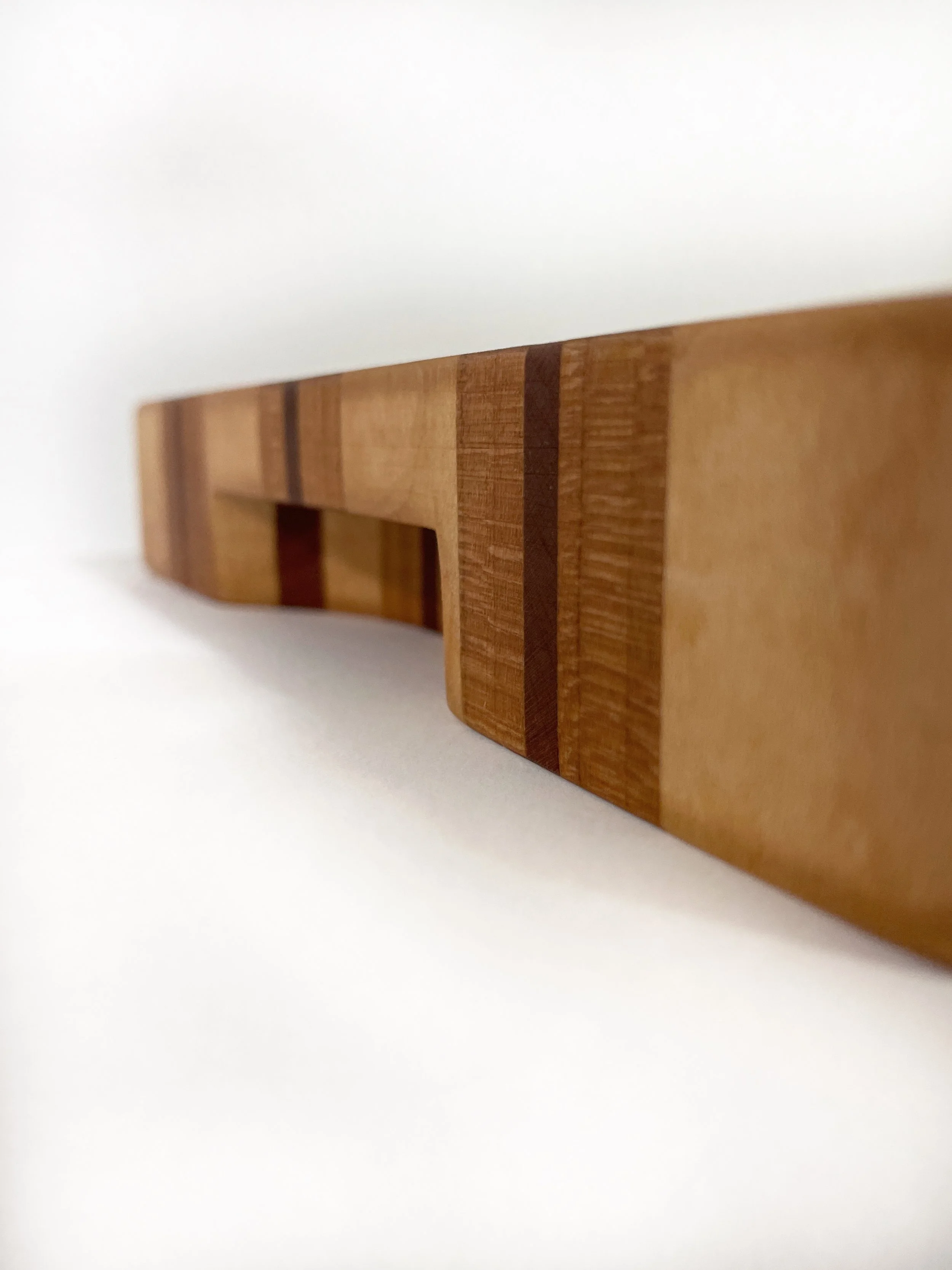 side view of Arden Noble cutting board highlighting contrasting maple, cherry, and walnut wood pattern