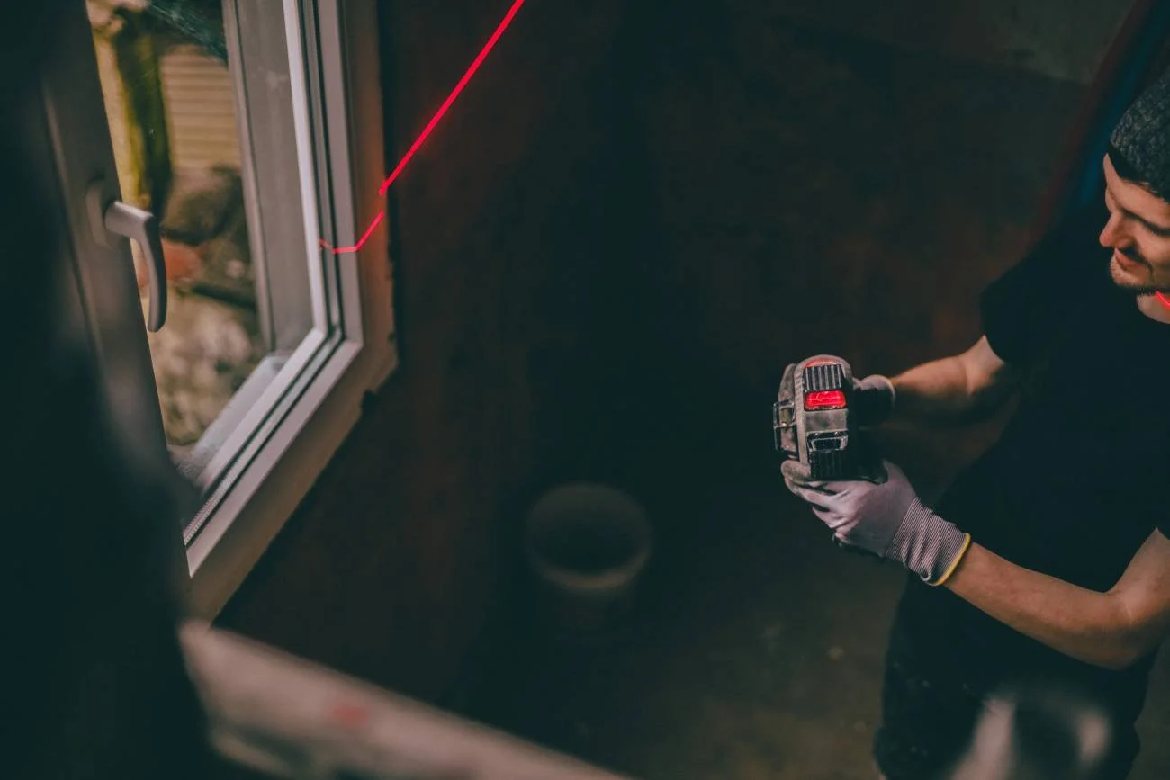 One young handsome Caucasian man in a black uniform stands in a house near the window